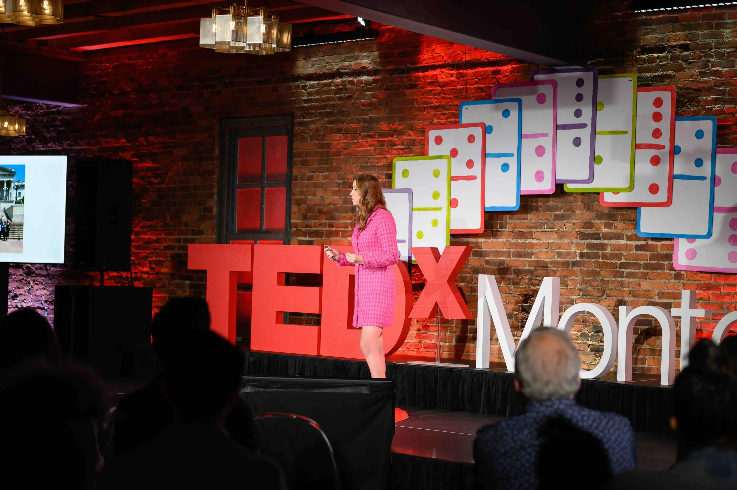 Speaker in a pink blazer presenting on stage at TEDx Montclair