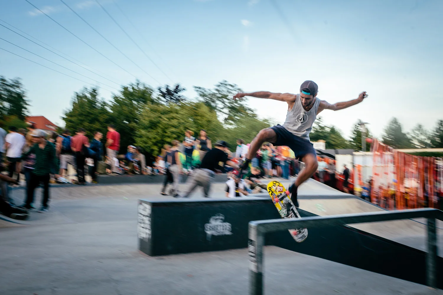 Skateboarder springt über ein Rail bei einem Skate-Contest vor Publikum.