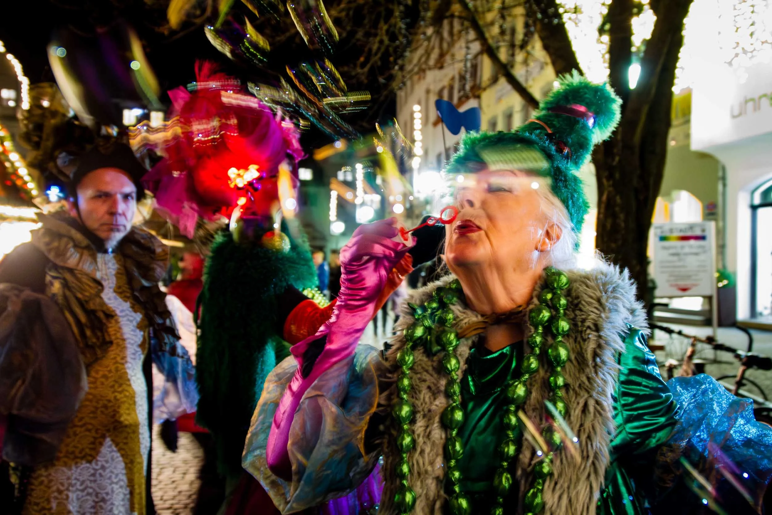 Frau in farbenfrohem Kostüm bei einem abendlichen Straßenfest. Eventfotografie.