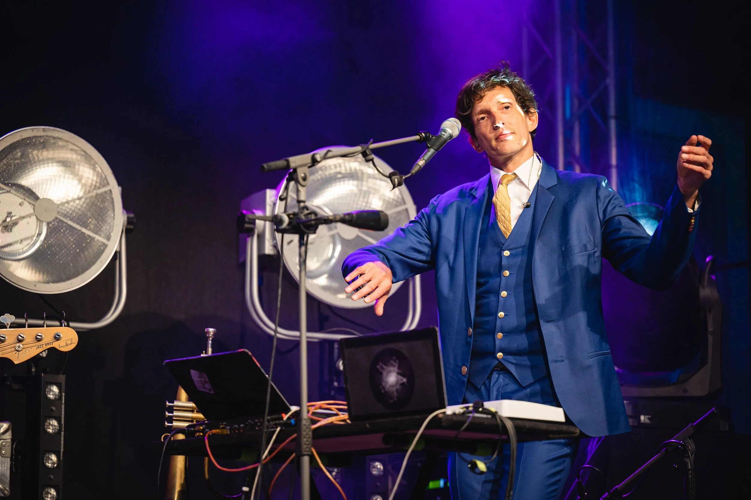 Musiker im blauen Anzug im Scheinwerferlicht auf der Bühne. Konzertfotografie.