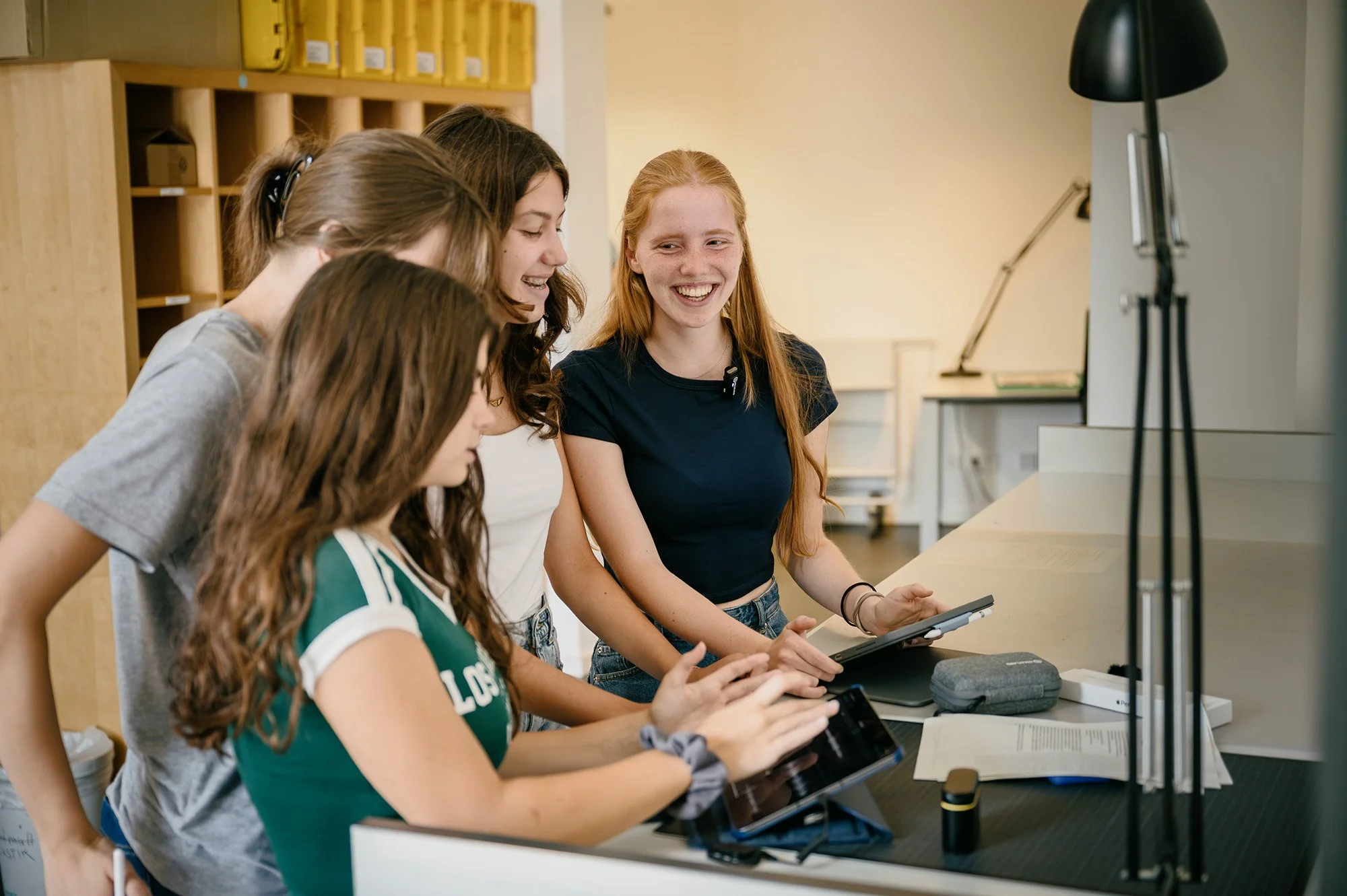 Junge Menschen in grünen Shirts bei einem Workshop am Laptop.