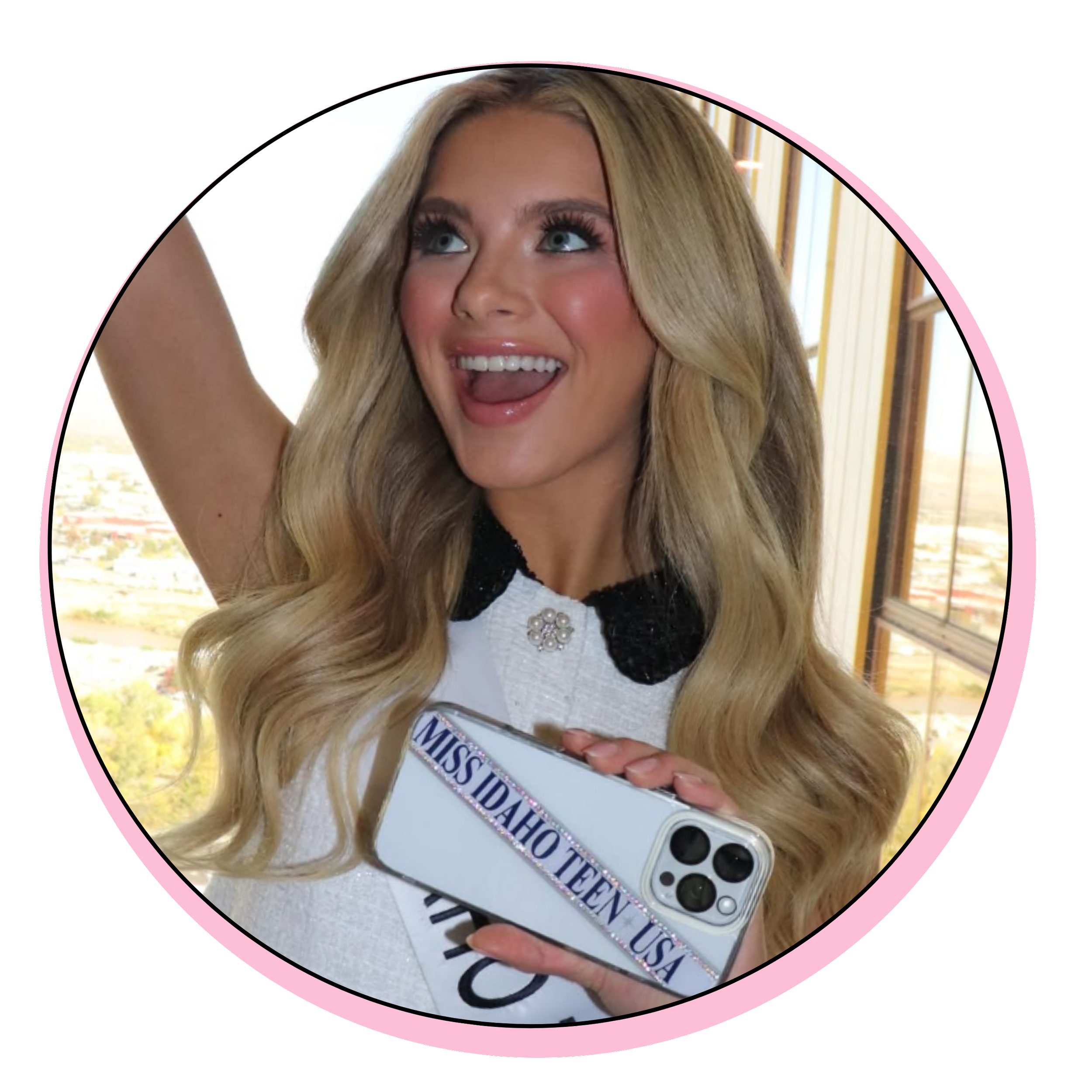 Miss Idaho Teen USA contestant taking a selfie, holding a phone with a Miss Idaho Teen USA sash, smiling and looking excited.