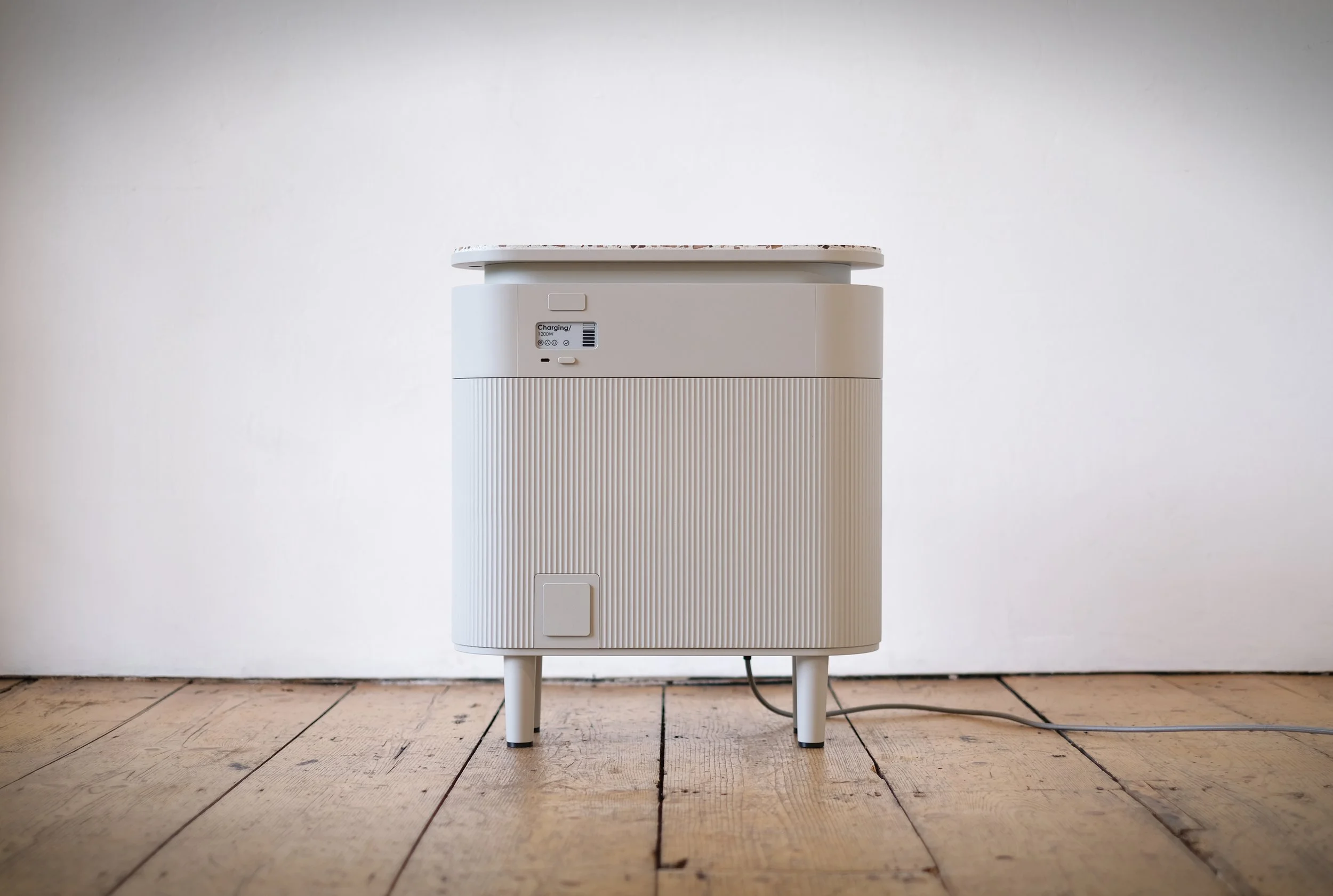 Front view of the Windfall plug-in home battery on a wooden floor, with its digital display showing active charging.