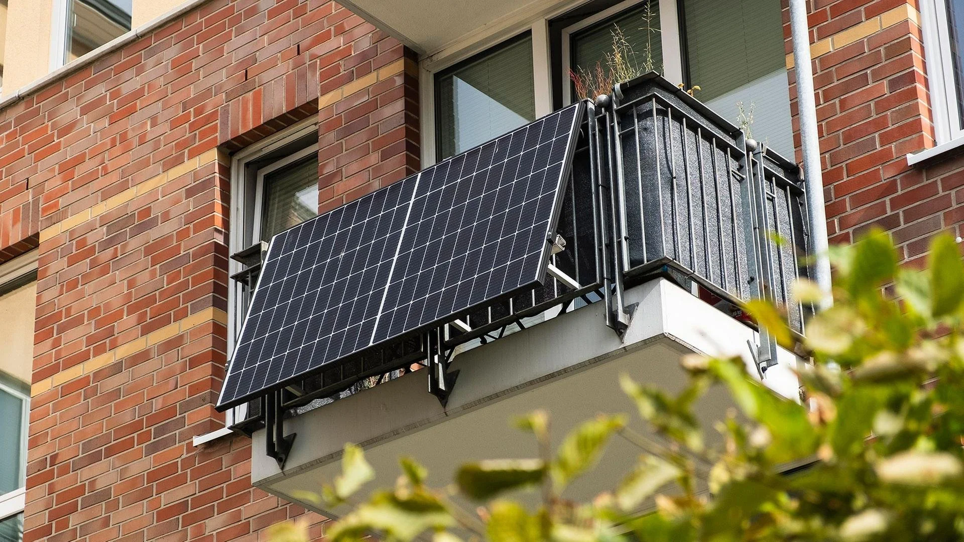Plug-in balcony solar panel system mounted on an urban brick apartment balcony rail.