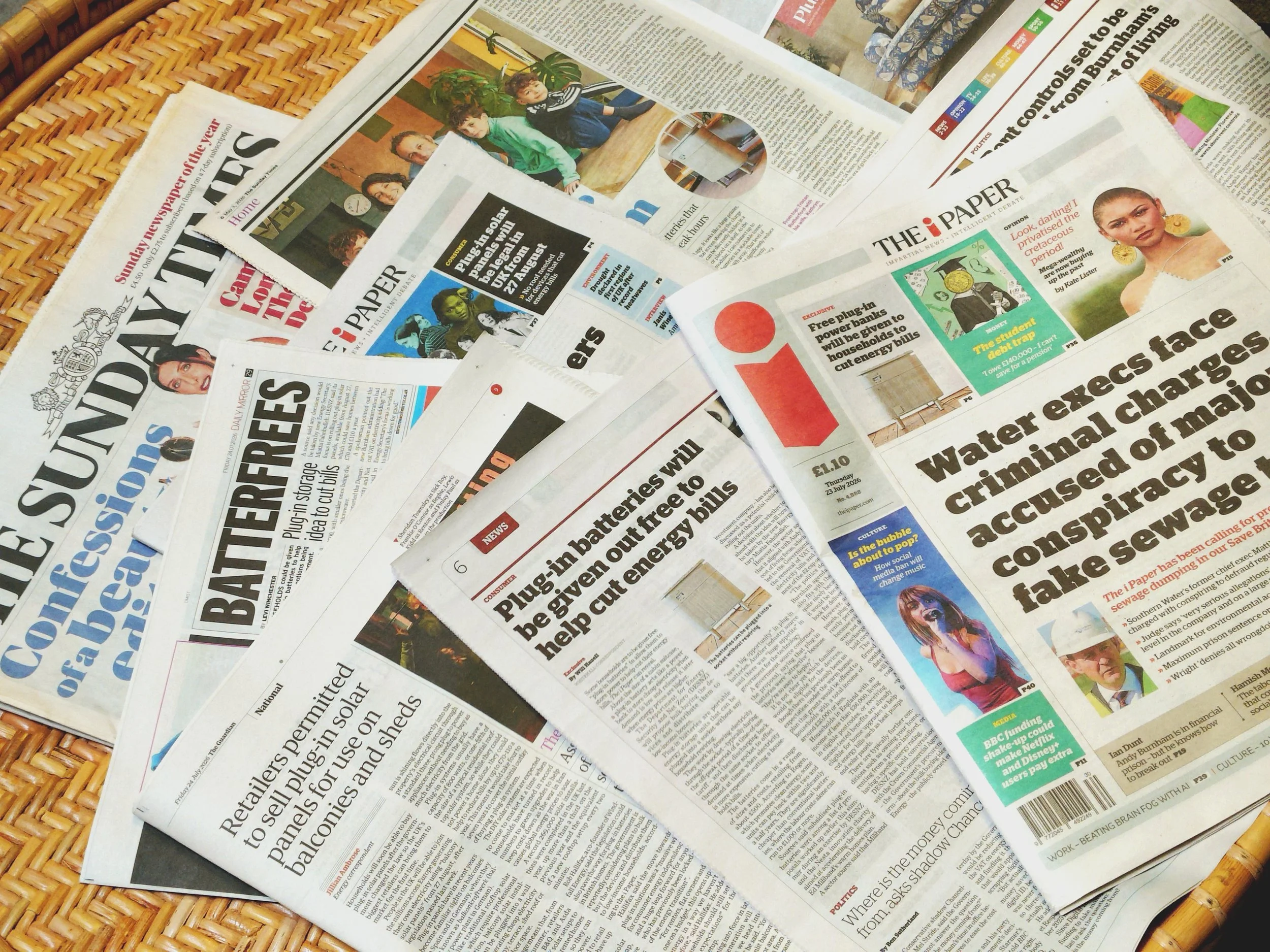Scattered UK newspapers featuring Windfall Battery press coverage on cutting household energy bills. Press such as: The Sunday Times, The I Paper, The Daily Mirror. Titles like: plug in batteries will be given out free to help cut energy bills