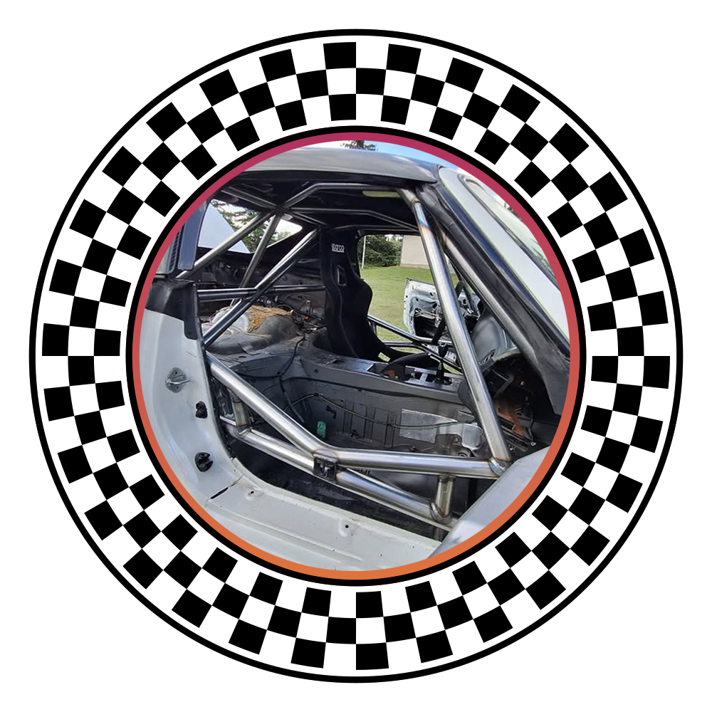 Interior of a race car showing a roll cage and racing seat with a harness.