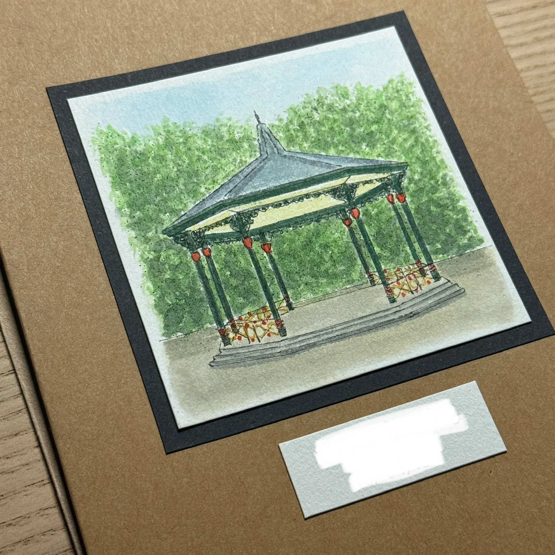 A watercolour painting of the Battersea bandstand surrounded by green trees for a bespoke wedding card.