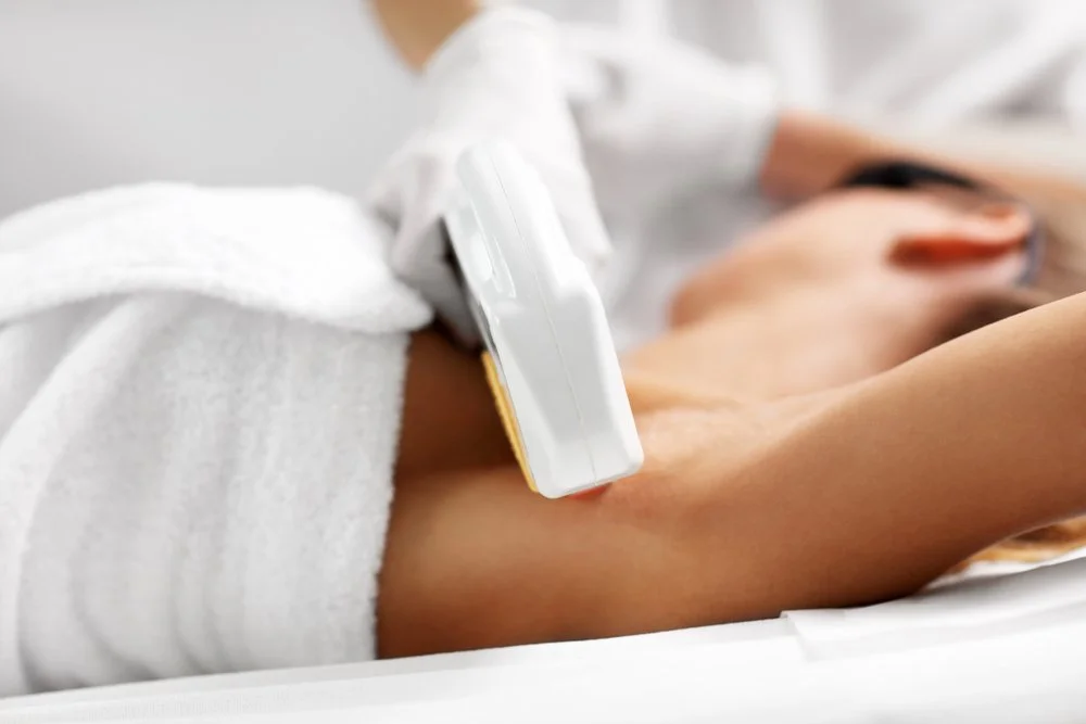 Person receiving an injection or vaccination in their upper arm, lying on a bed or examination table.