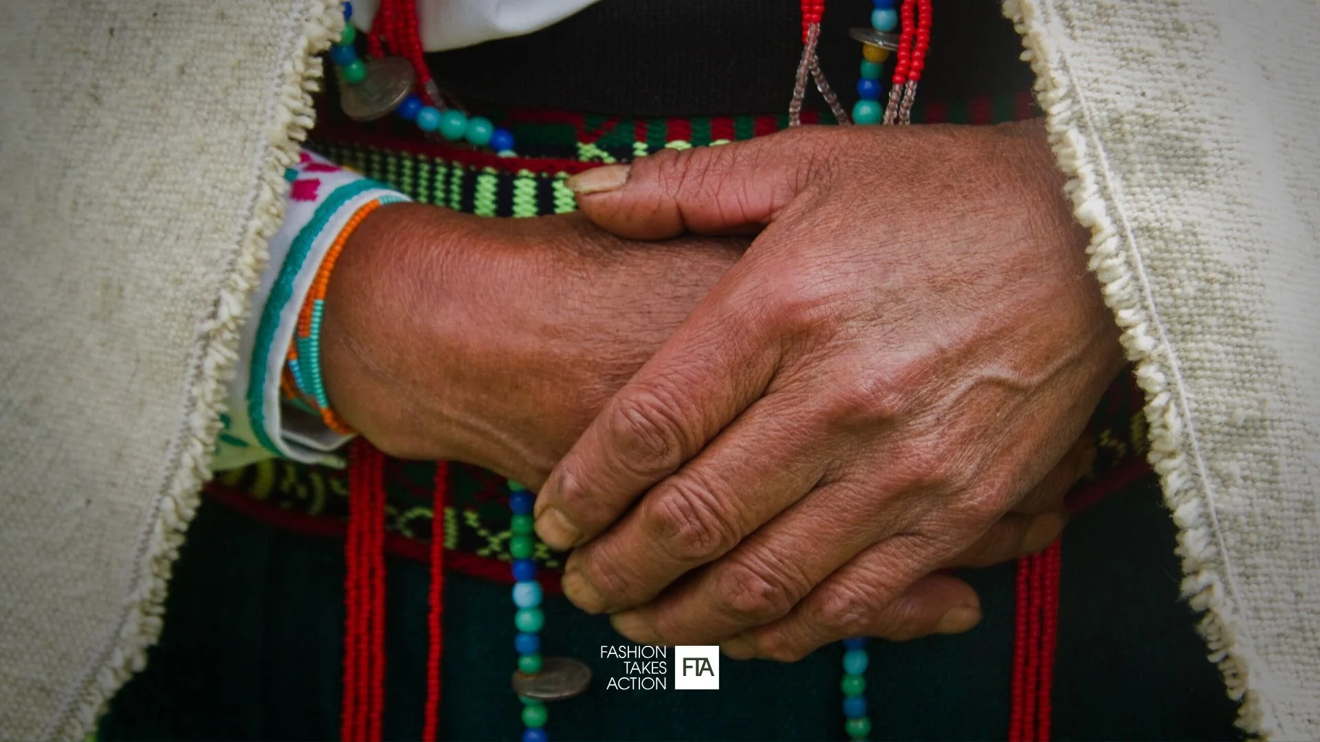 Indigenous man holding hands clasped together in front of his body.