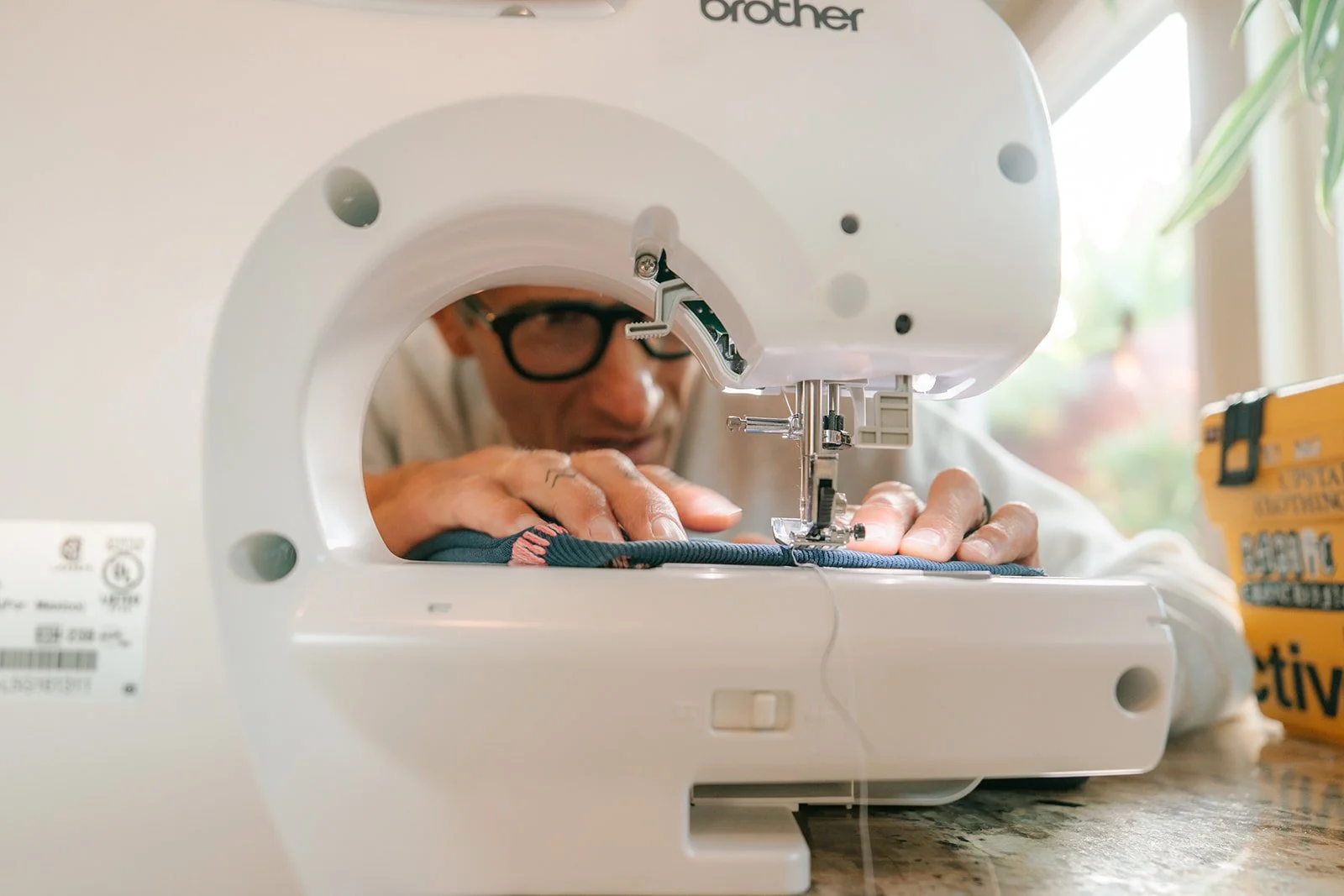 Man with glasses sewing