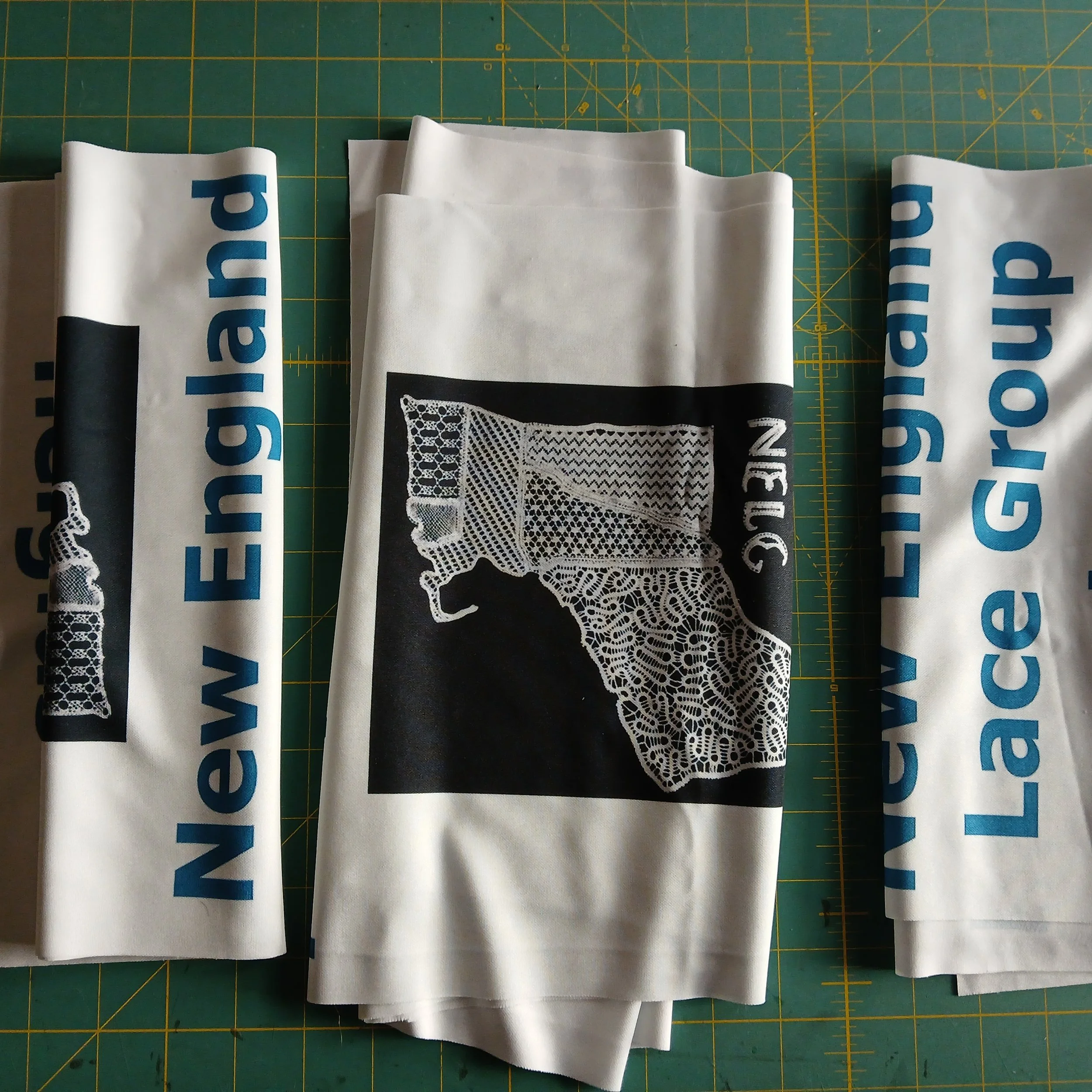 Today's lace-adjacent task: I had to cut up the new banners we had made. See the white table runner things we use at displays? New England Lace Group and our URL. 

We get them printed with our logo and I can get 3 to a yard at @spoonflower [I am not