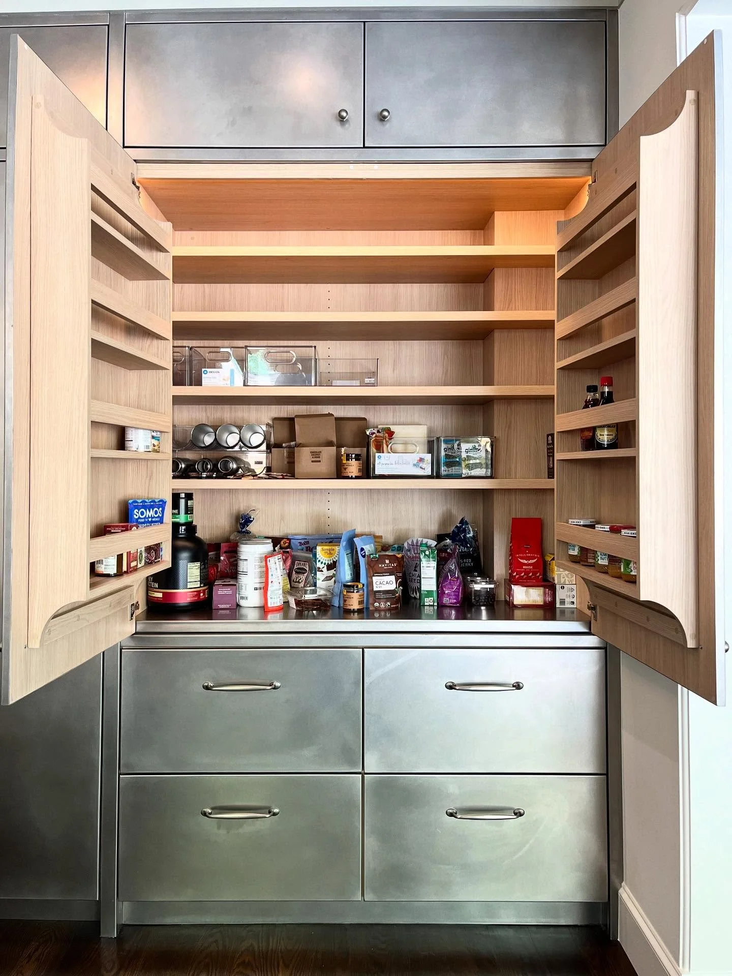 Kitchen Pantry storage behind large stainless steel clad Vicenza Oak doors with custom-made shelving rack system designed by @leascheinstudio ✨ 

Swipe for more!