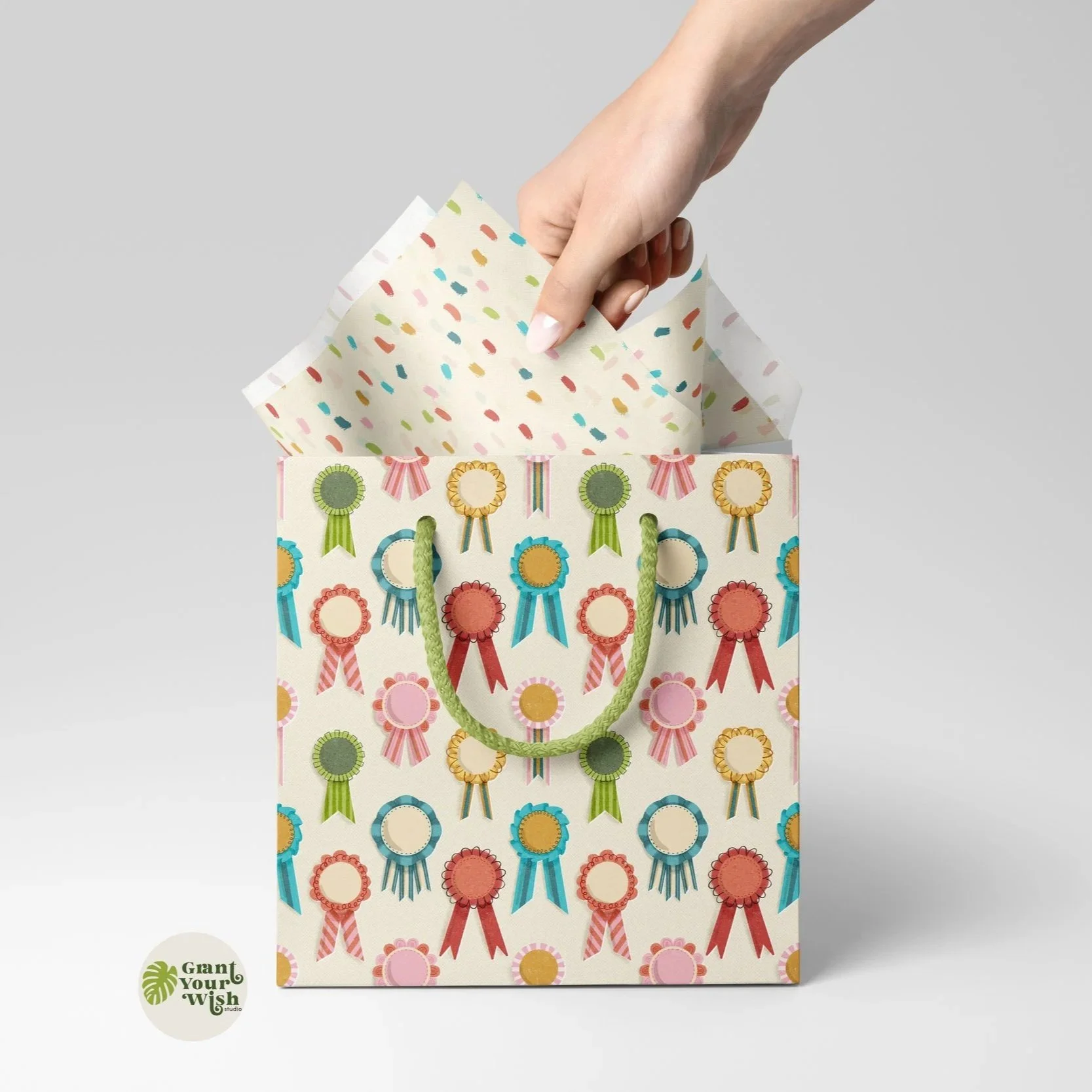 Decorative gift bag with colorful medal and ribbon prints, with a hand placing tissue paper into it.