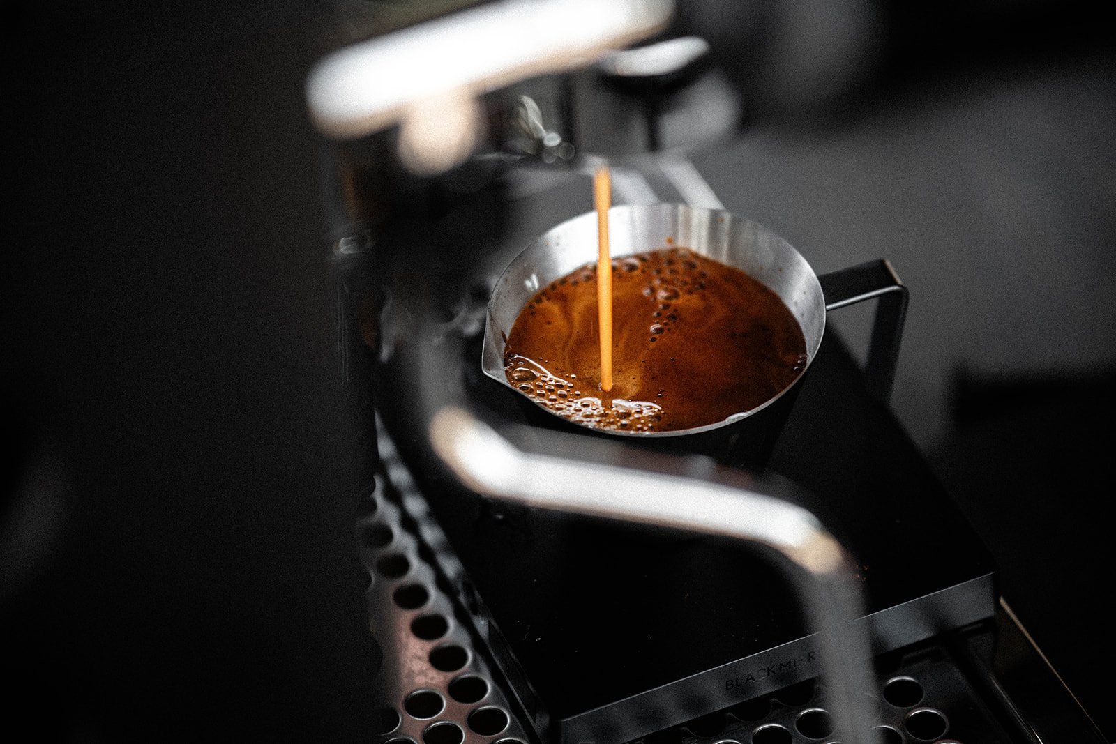 Espresso pouring into a metal cup from a coffee machine.