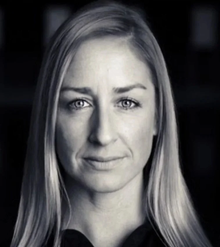 Black and white portrait of a woman with long hair, looking directly at the camera with a slight smile.