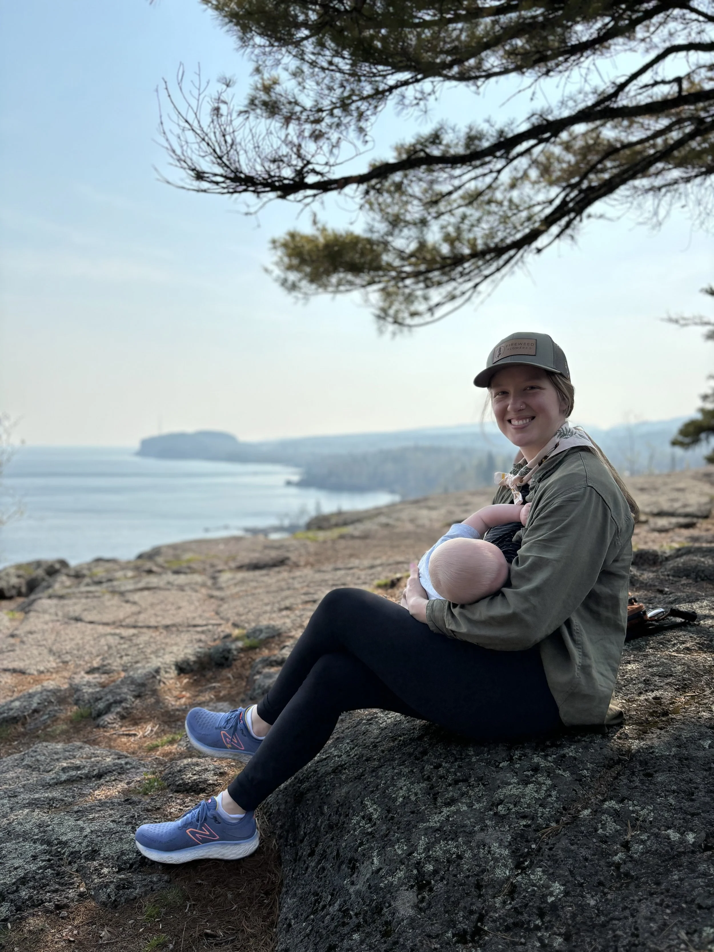 madeline sitting outdoors breastfeeding an infant
