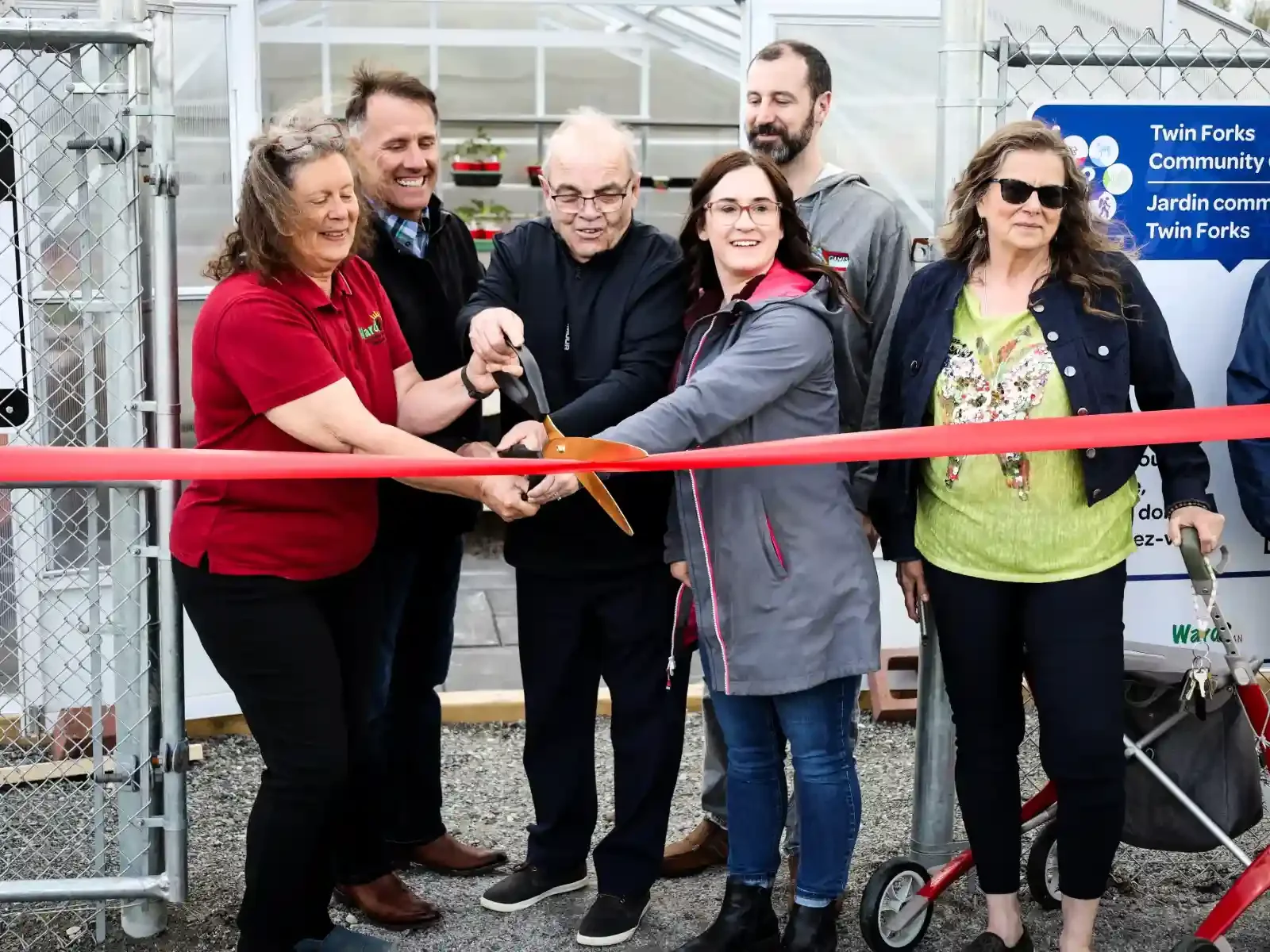 Group of people at a ribbon-cutting ceremony outside a greenhouse