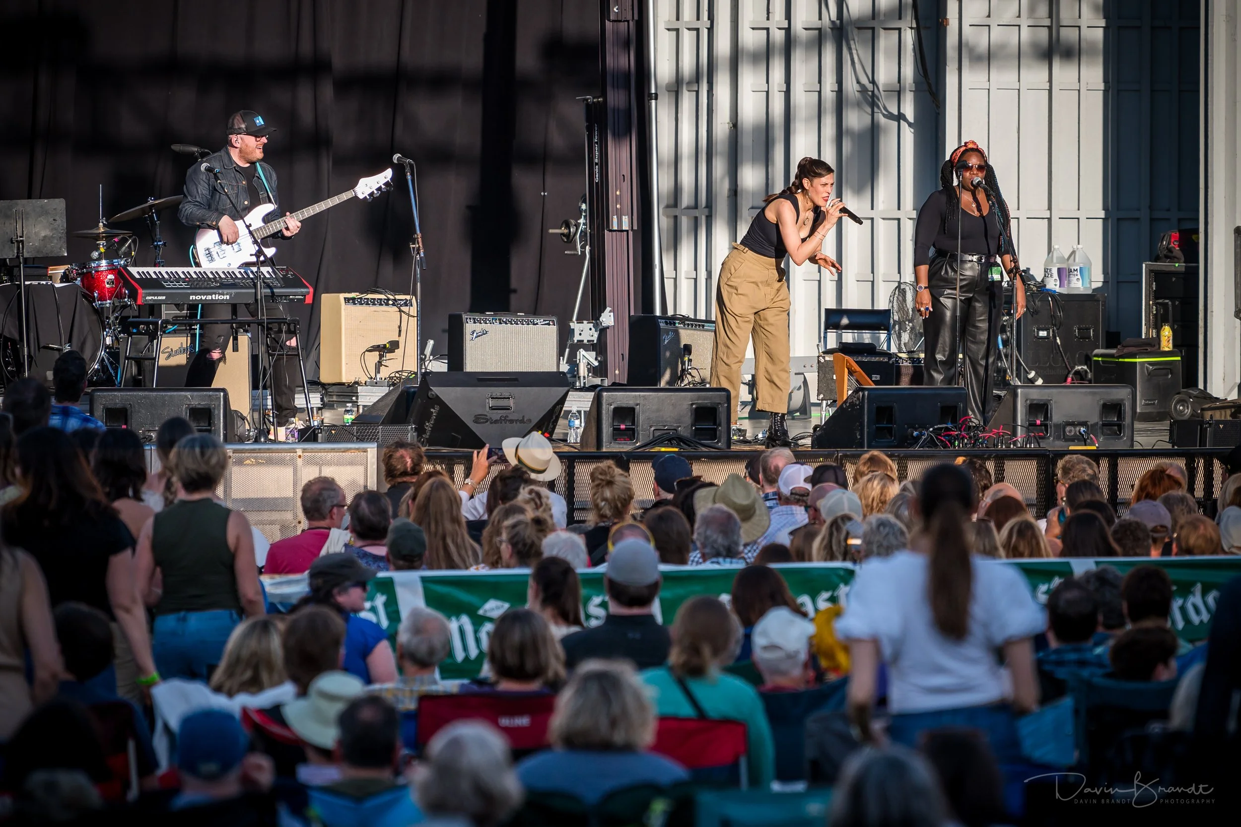 A live outdoor music concert with a band performing on stage and an audience watching.