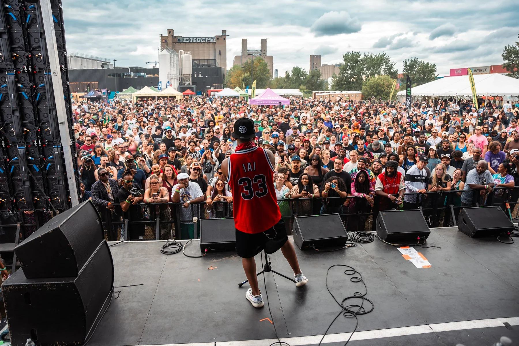 Lupe Fiasco performing on stage facing a large, diverse crowd at the 2025 Legacy Cup.