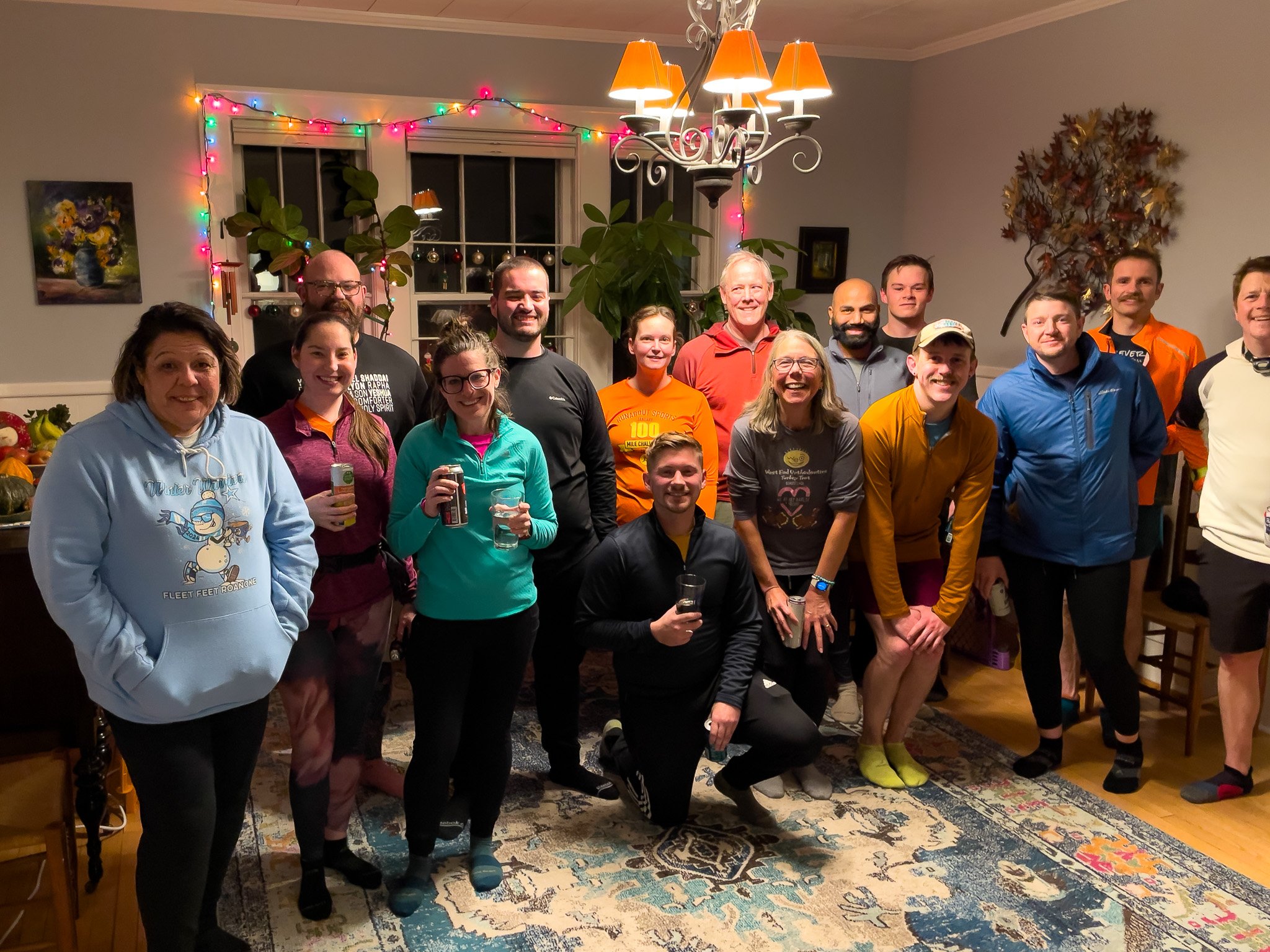 Group of people celebrating indoors with drinks, colorful lights, and festive decorations.