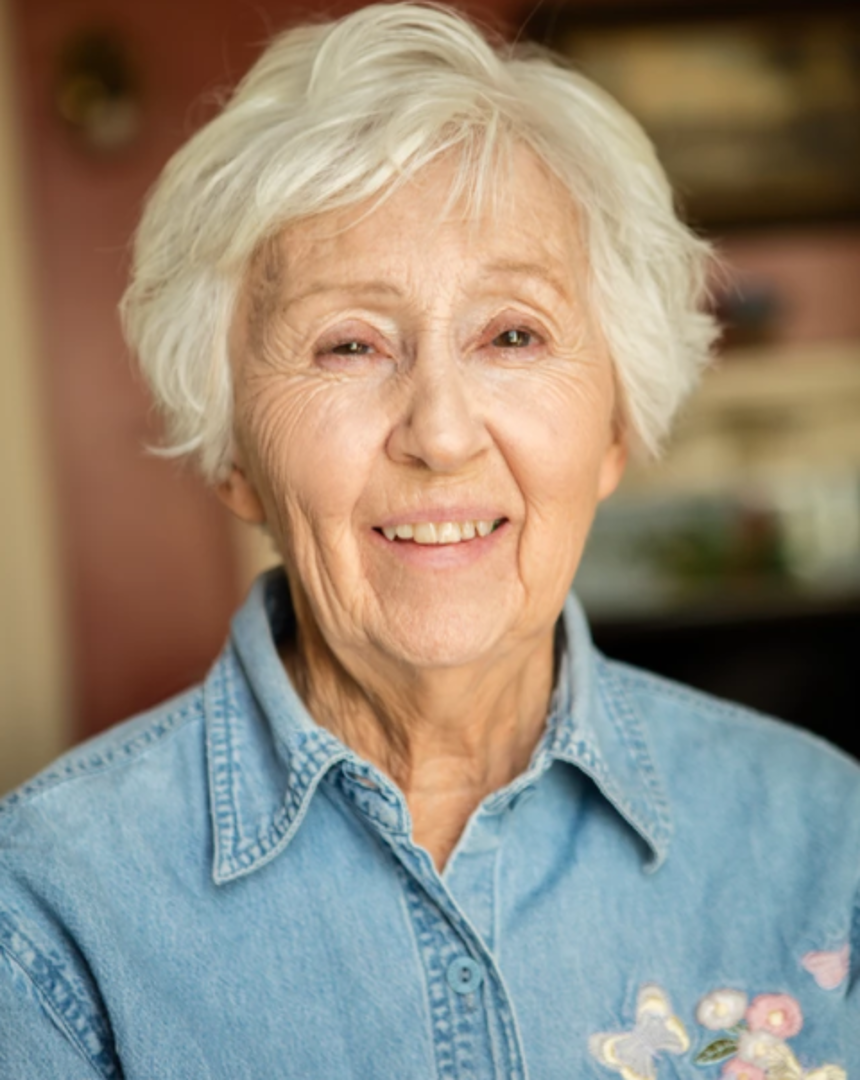 An elderly woman with white hair smiling at the camera.