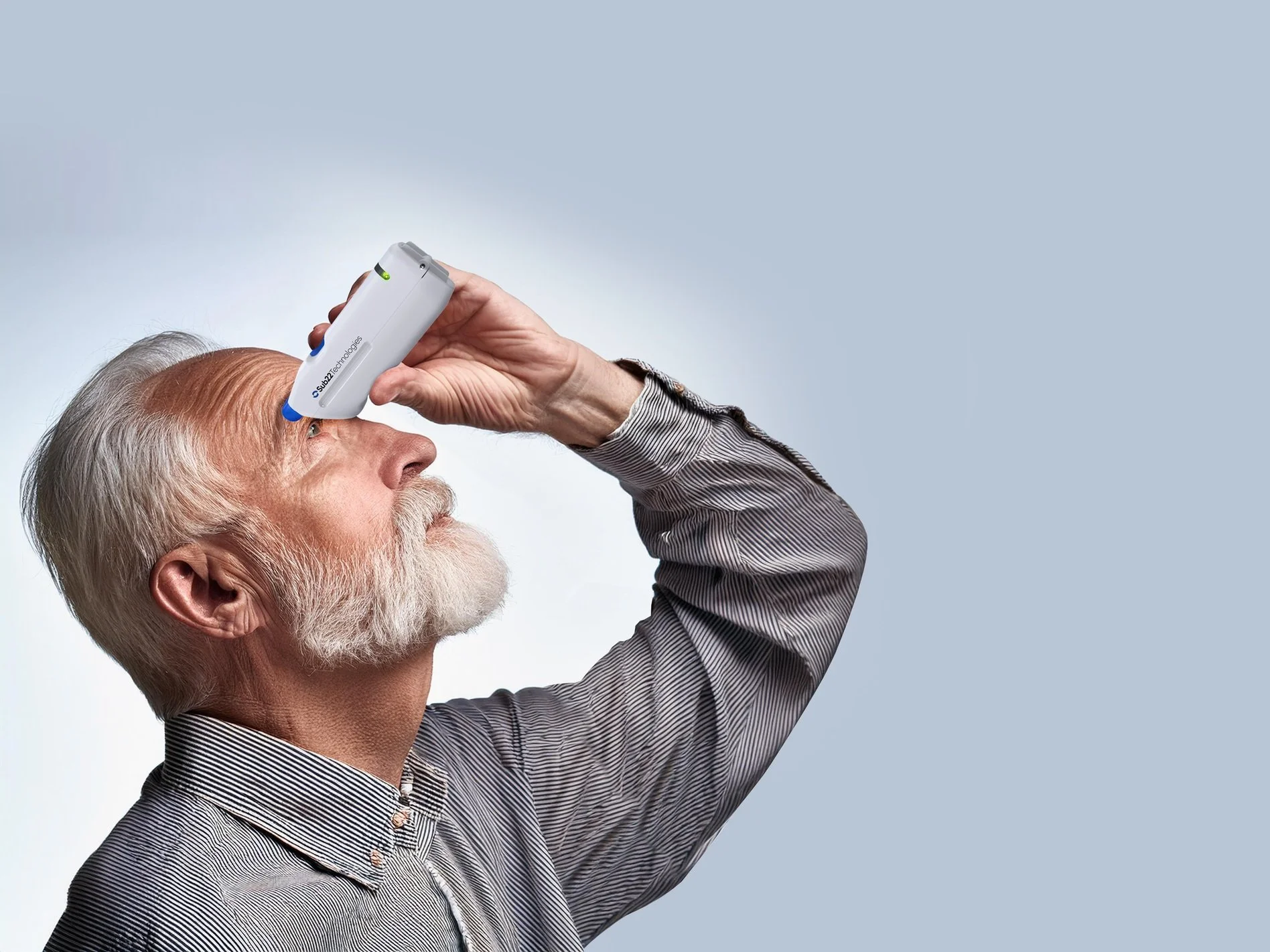An elderly man with white hair and beard using the OVI smart eye dropper.