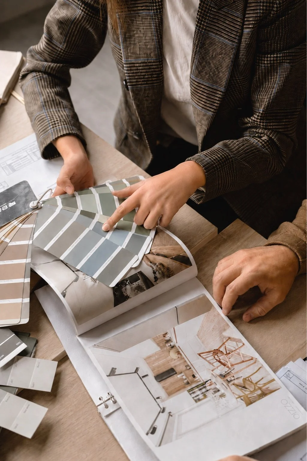  Interior stylist reviewing neutral colour swatches and design references — illustrative example 