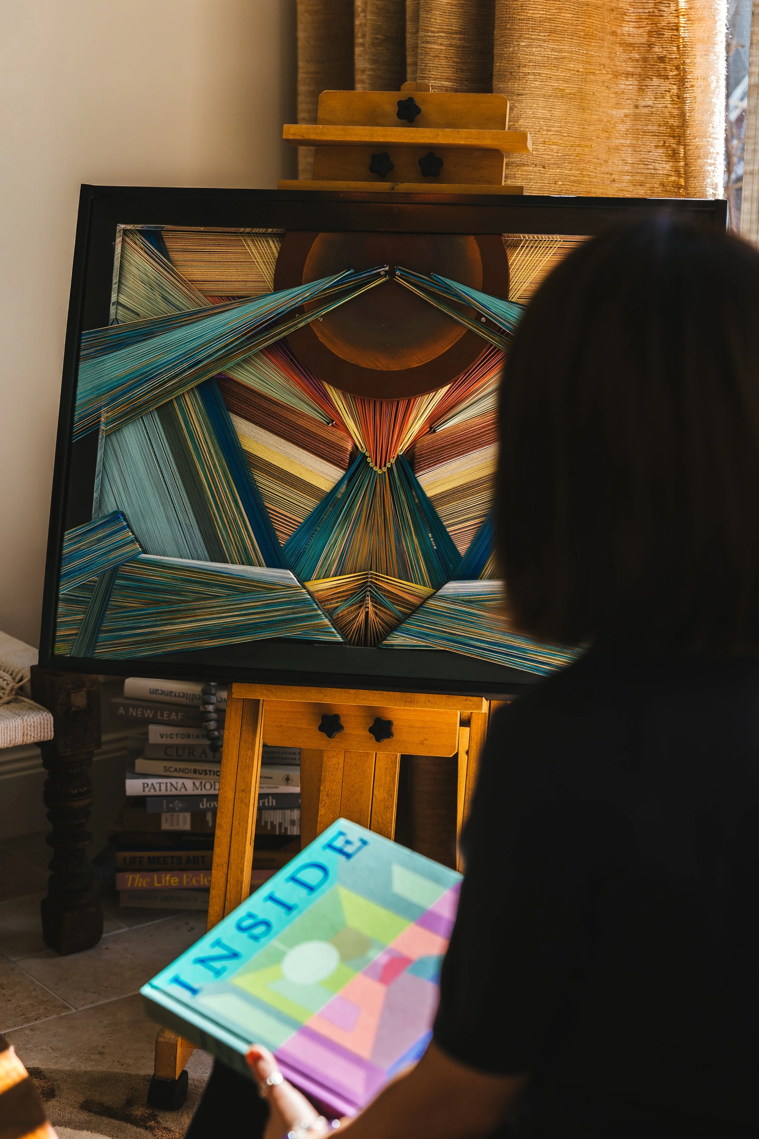 A geometric textile artwork displayed on a wooden easel in a warm interior setting — art advisory and interior styling, Sydney and beyond, SYP Homes