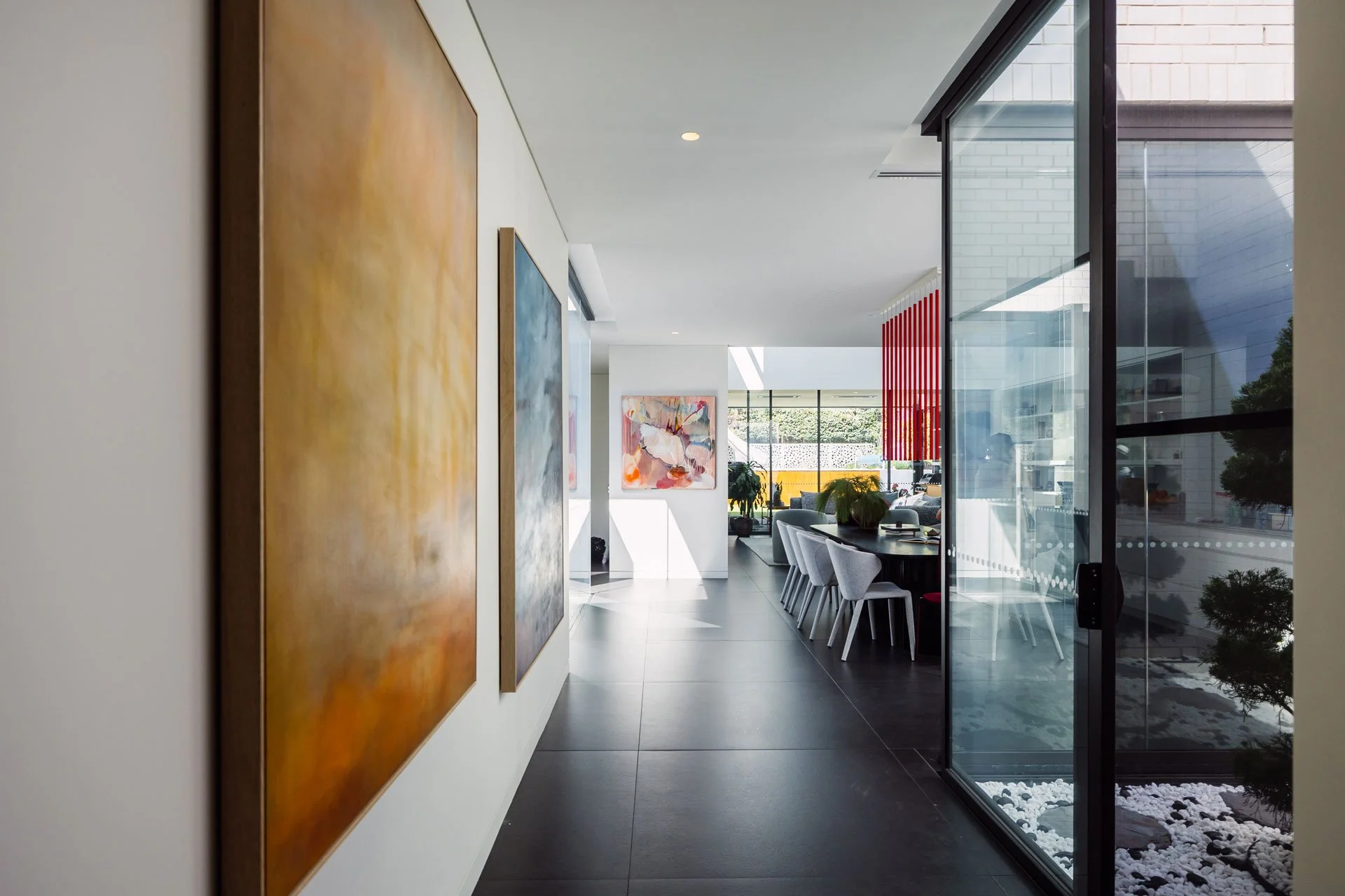 curated contemporary artwork placed within a modern residential interior hallway leading to a dining and living space