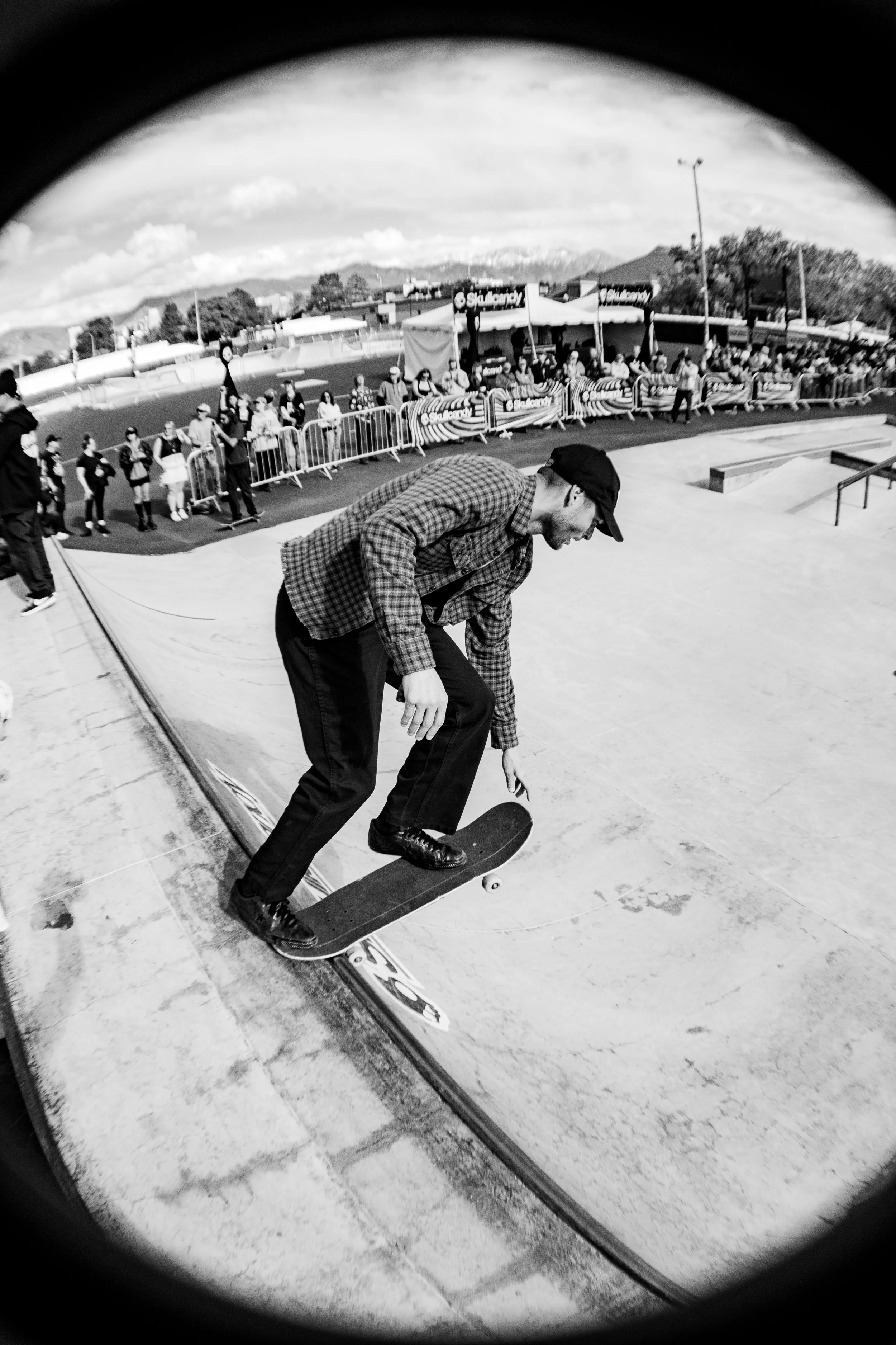 A man skating at a skate park with spectators watching in the background.