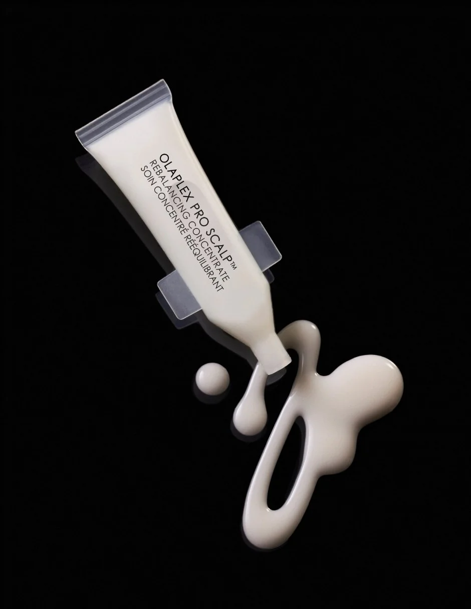 Un tube de crème de soin visage blanc avec le texte 'OLALEX PRO SCALP REBALANCING CONCENTRATE SOIN CENTRE RELUQUANT' et un cercle blanc, avec de la crème blanche écoulée sur un fond noir.
