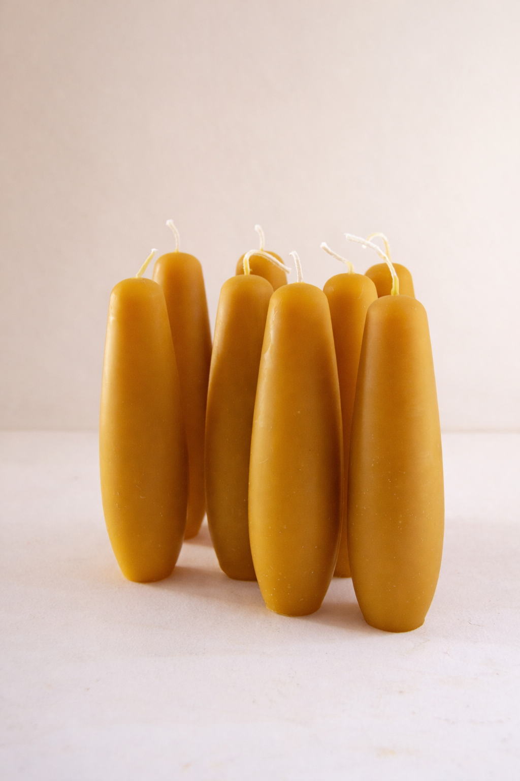 Tapered stubby beeswax candles, handmade for long burning clean unscented candlelight. Group of spindle candles together in natural lighting.