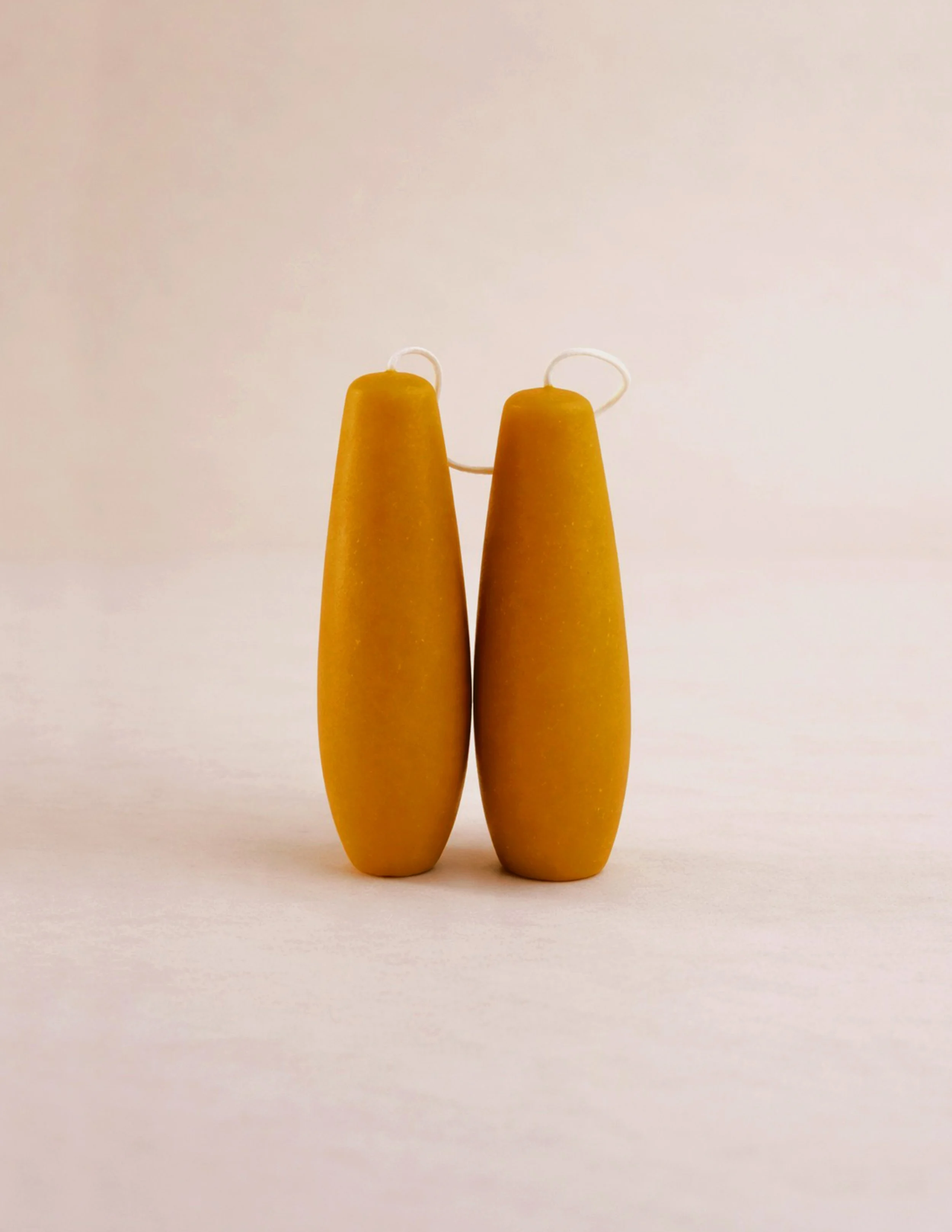 Tapered stubby beeswax candles, handmade for long burning clean unscented candlelight. Pair of spindle candles together in natural lighting.