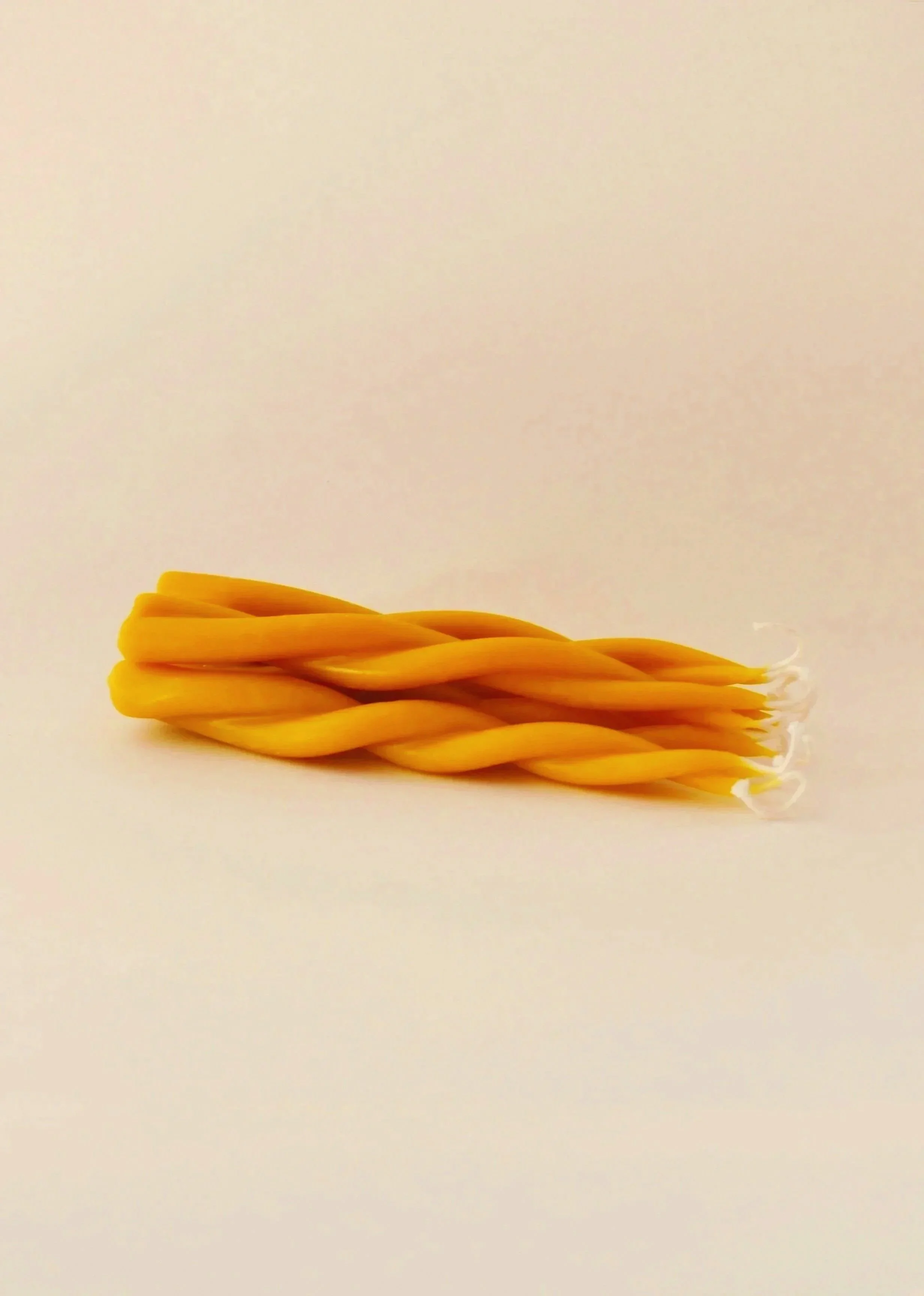 A bundle of yellow twisted candles on a plain white background.