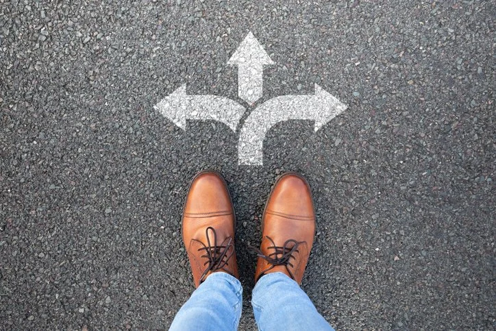 Feet positioned at a crossroads, representing career decision-making and professional pivots