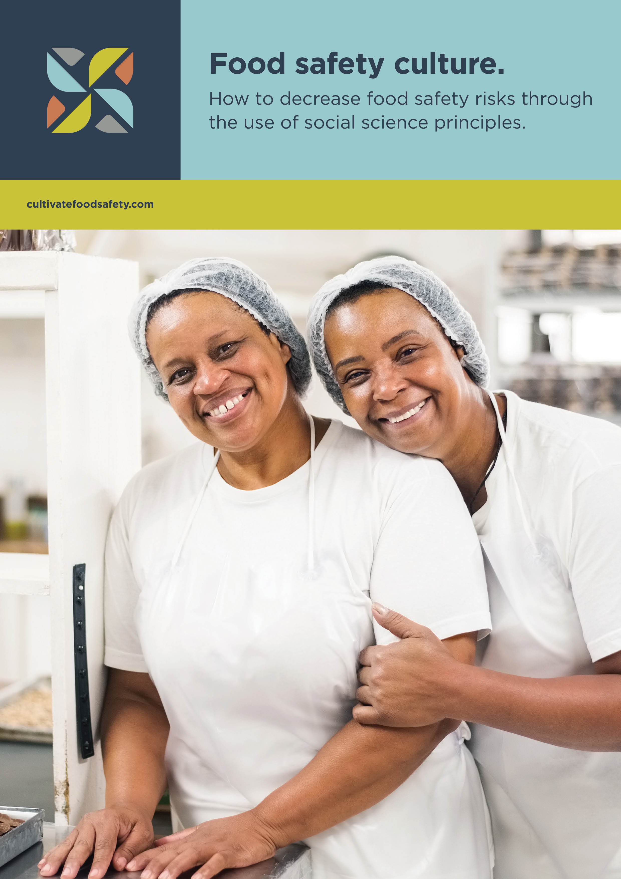 Two smiling workers in white uniforms and hairnets in a kitchen, promoting food safety culture.
