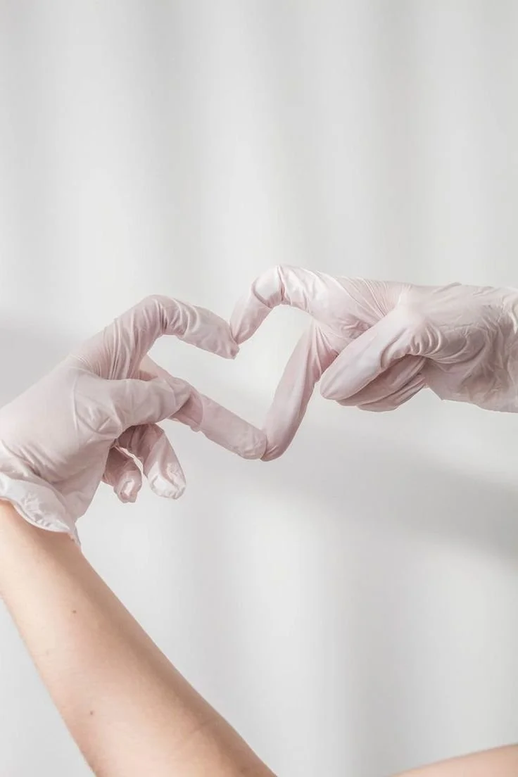 Two hands wearing white gloves forming a heart with their fingers.