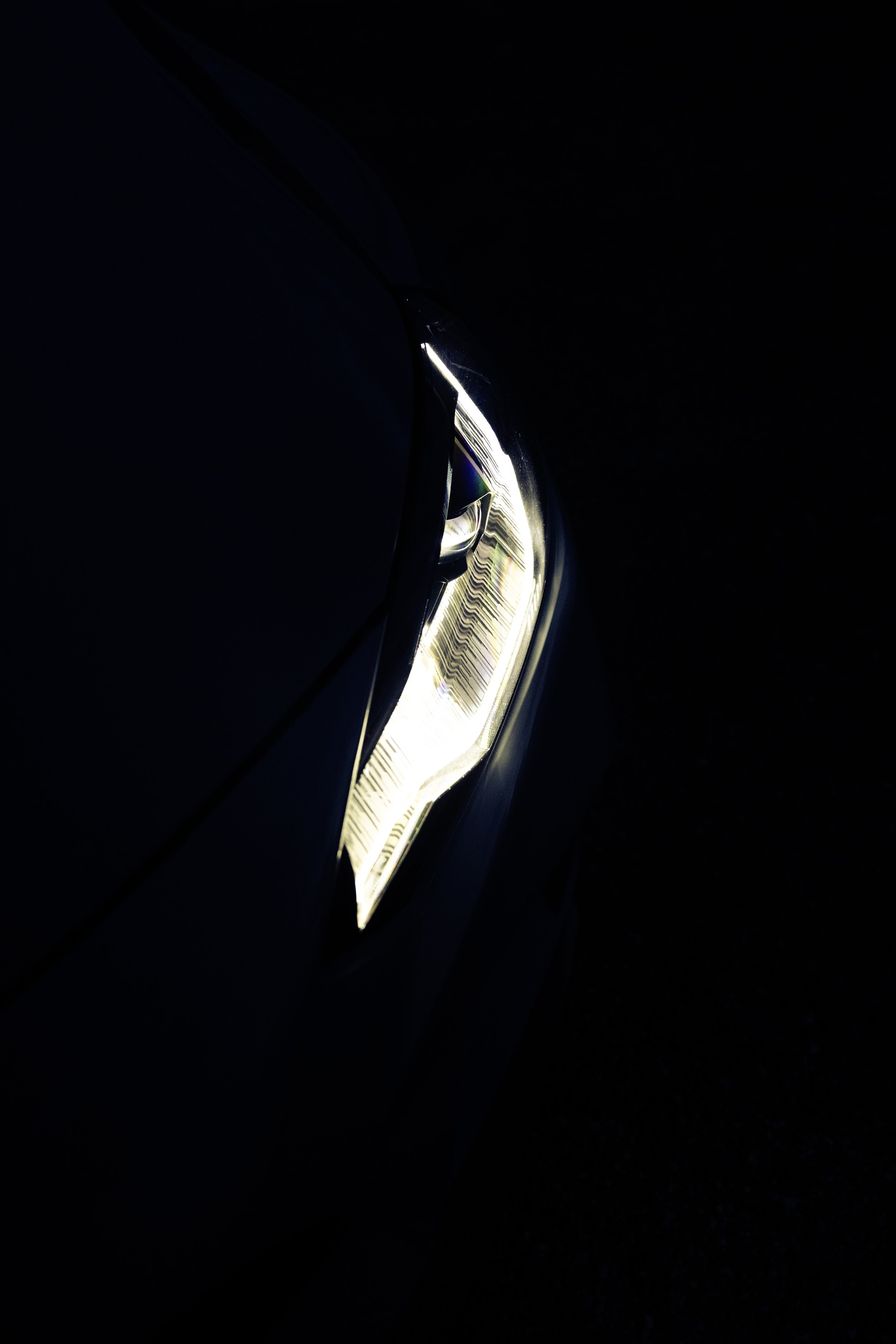 Close-up of a car's headlight turned on in a dark environment.