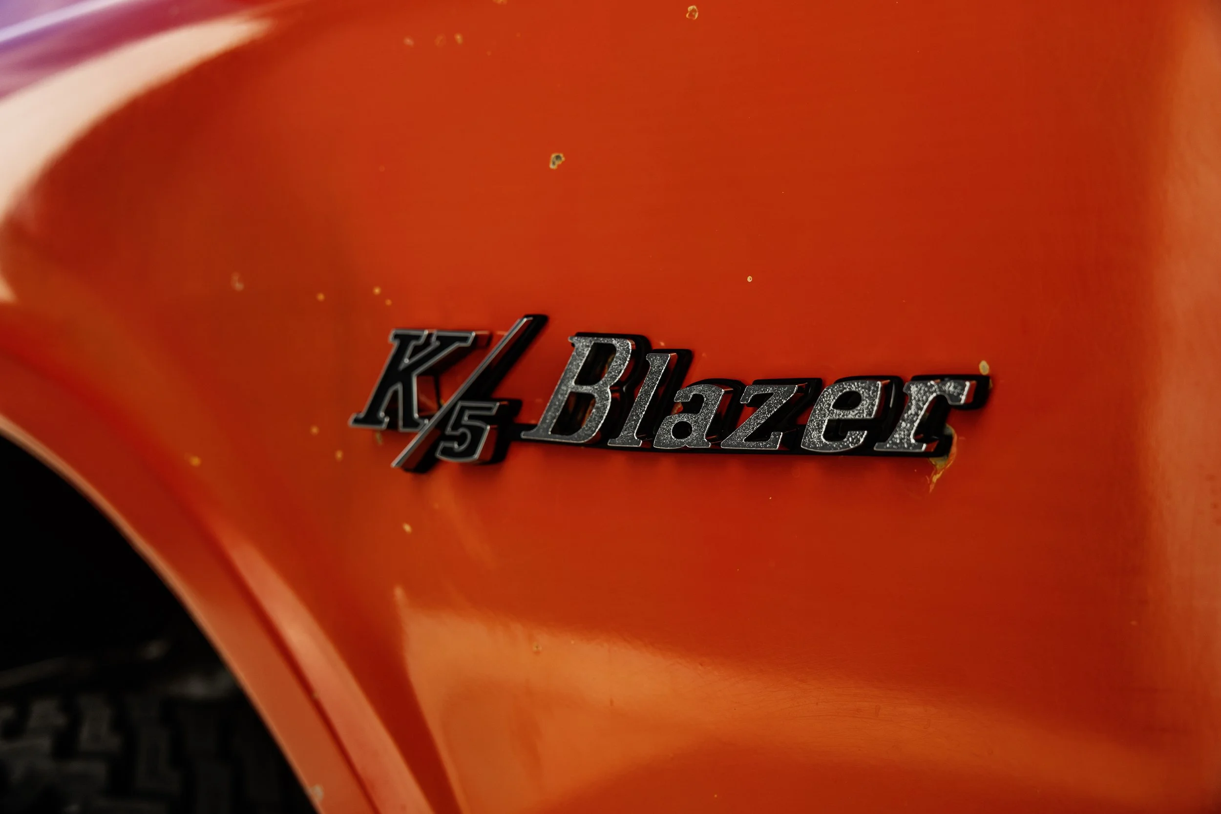 Close-up of a red vehicle's body with a badge that reads 'K/5 Blazer' on it.