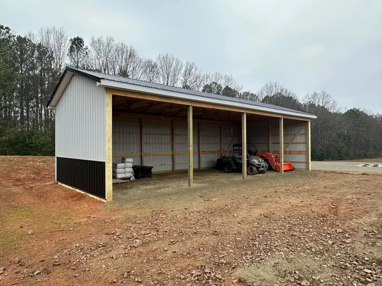 White 4-bay open-front tractor shed with black wainscot for farm equipment storage