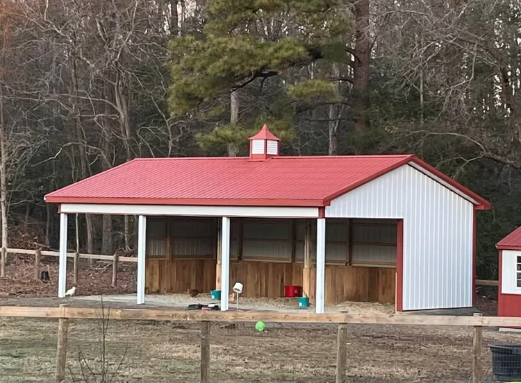 White 3-stall horse shelter with red metal roof and cupola, an open-front pole barn