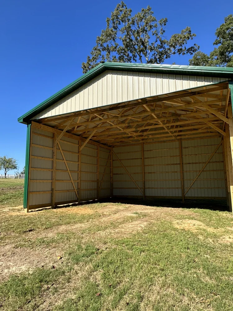 Three-sided pole barn for hay storage with light walls and green trim