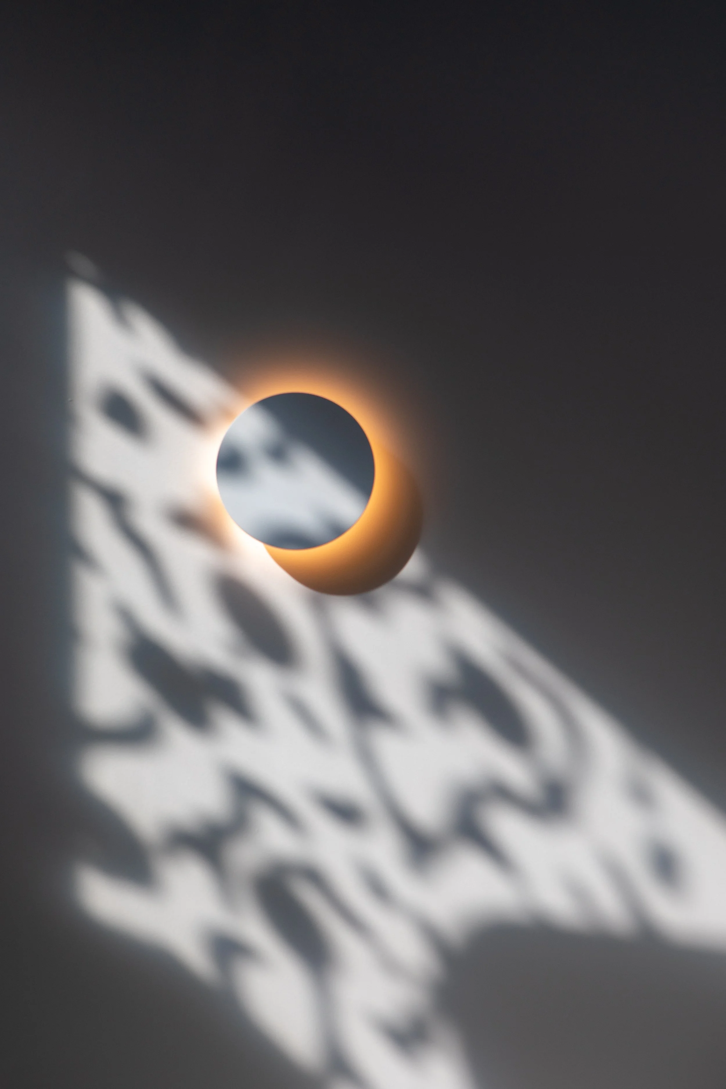 A round ceiling light fixture casting intricate shadow patterns on the wall.