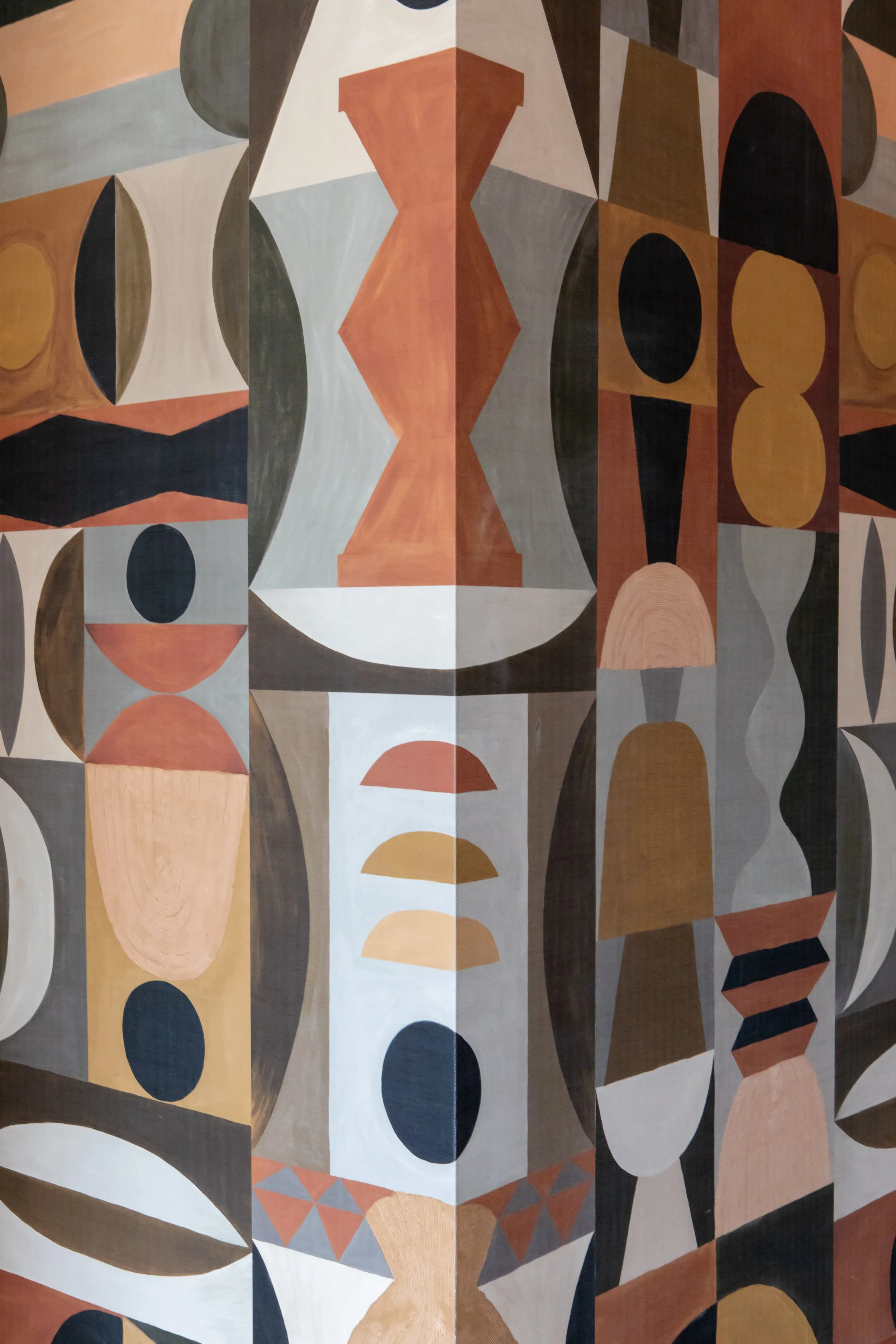 An abstract geometric mural with various shapes and earth-tone colors including browns, oranges, blacks, and greys.