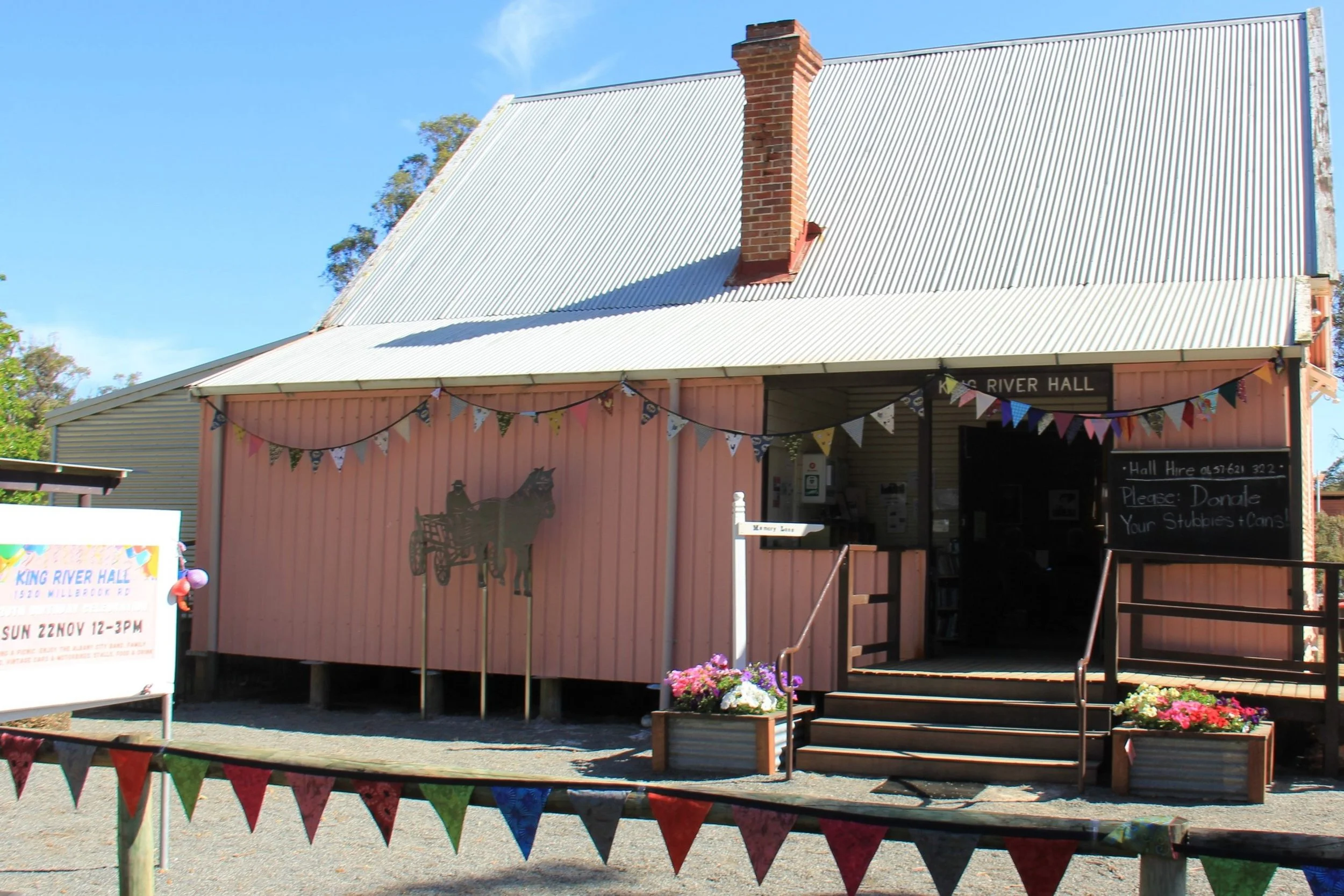 Historical community hall with bunting and flowers, sign on building "King River Hall".