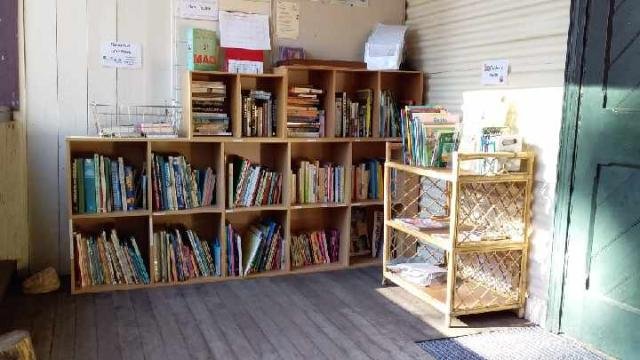 Wooden bookshelves filled with various books in a small indoor space with a wooden floor.