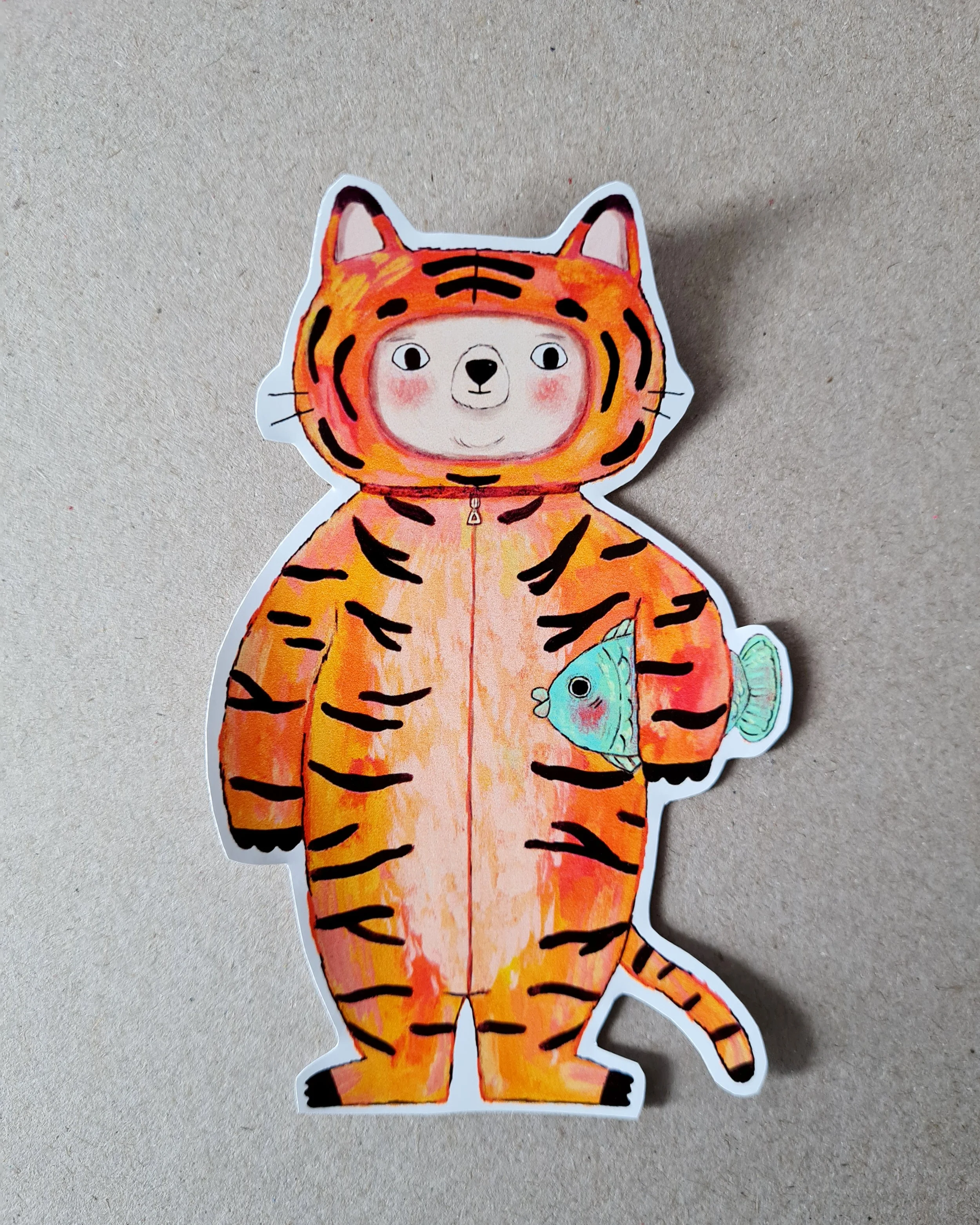 a bear dressed up as a tiger holding a fish and smiling