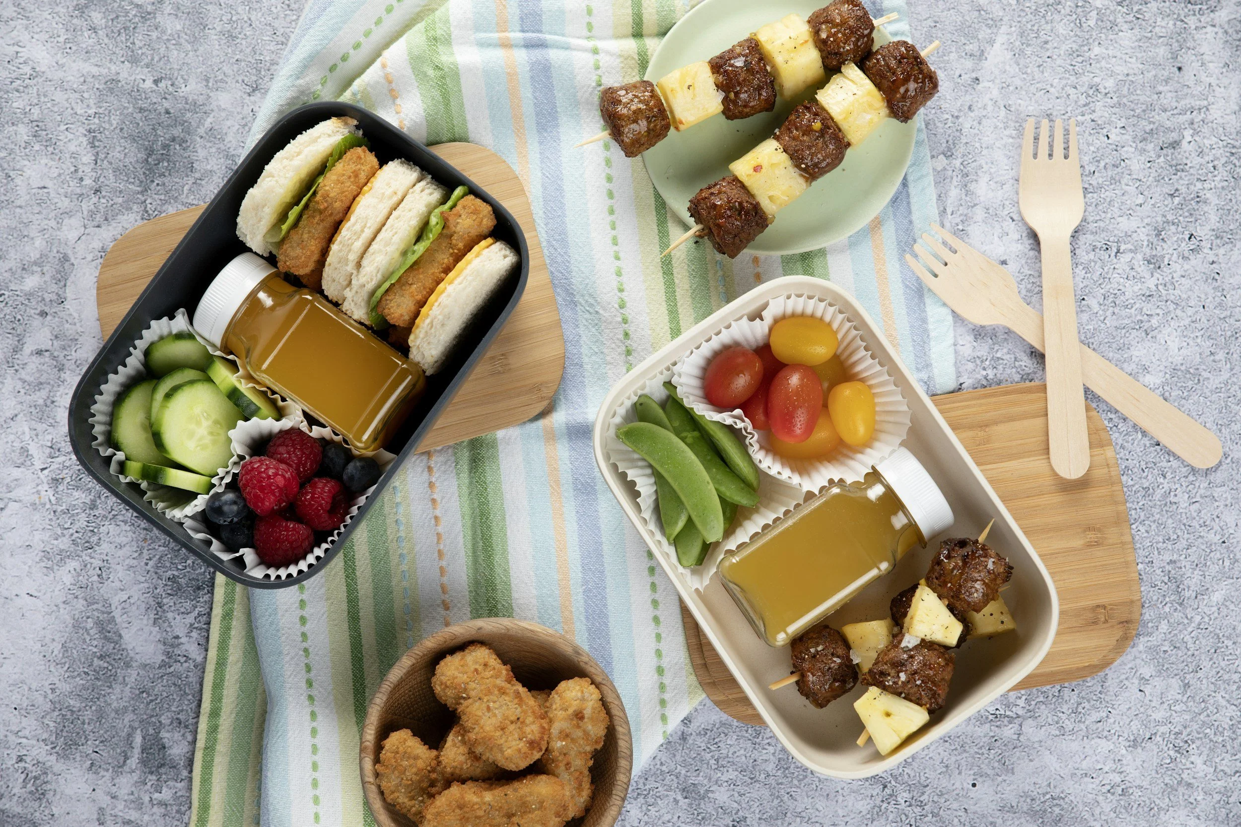 Overhead view of two healthy school lunchboxes packed with sandwiches, fruit, vegetables, and protein — back to school meal prep for moms