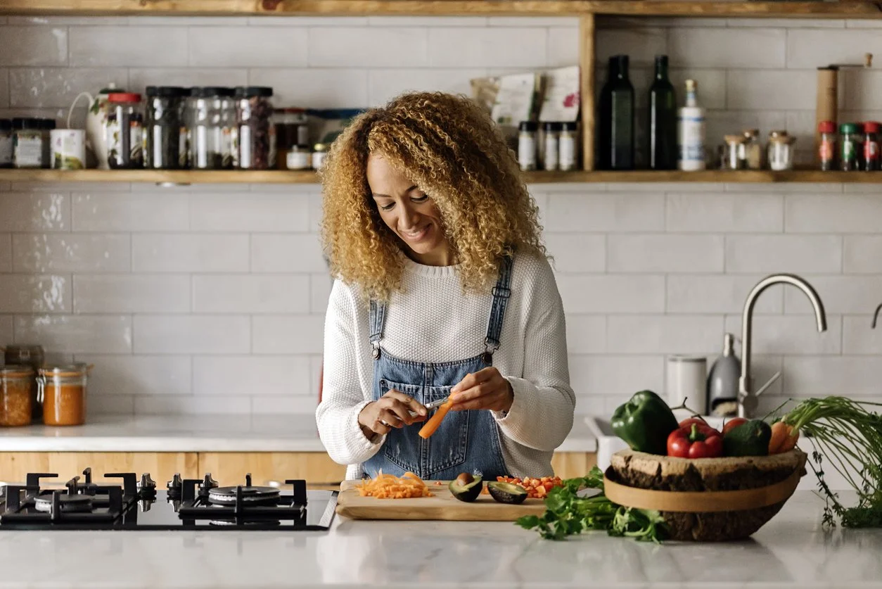 Woman preparing a balanced meal with protein and vegetables to manage menopause cravings and stabilize appetite.