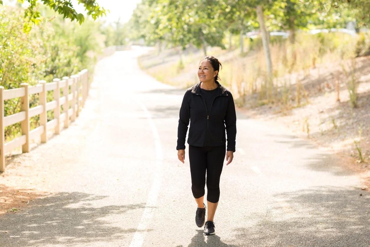 Woman walking outdoors in morning sunlight to boost energy naturally and support circadian rhythm.